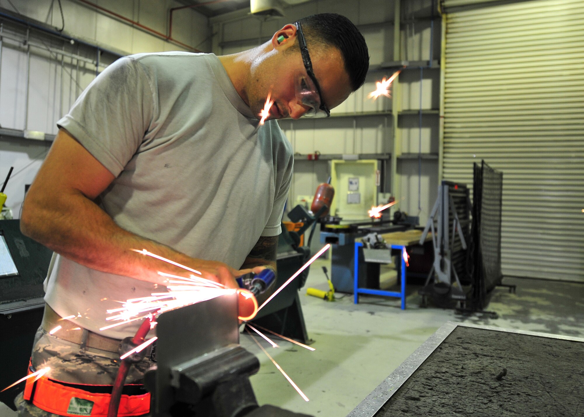 Air Force Senior Airman Cody Borden, 380th Expeditionary Maintenance Squadron Aircraft Structural Maintenance journeyman, uses a pneumatic sander to file a sheet metal patch at an undisclosed location in Southwest Asia, April 1, 2014. Aircraft structural maintainers maintain the structural integrity of aircraft by assembling and reparing structural parts and components. Borden is a native of Newport News, Va., and is deployed from Tinker Air Force Base, Okla. (U.S. Air Force photo by Staff Sgt. Michael Means/Released)