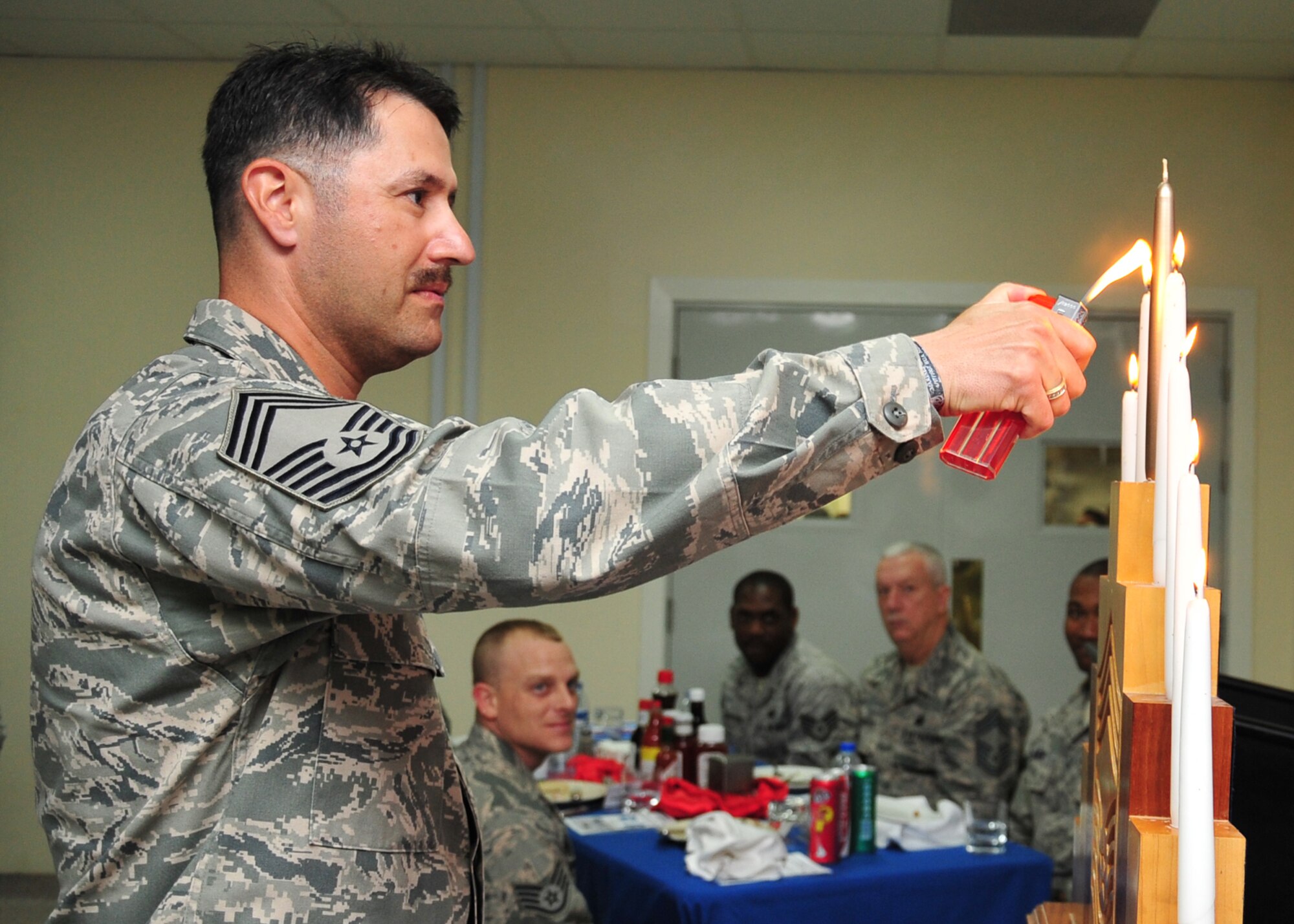Chief Master Sgt. Marcus Quintero, newest inductee, lights the final candle during the candle lighting ceremony representing his journey to chief at an undisclosed location in Southwest Asia, March 31, 2014. Quintero is assigned to the 380th Expeditionary Civil Engineer Squadron and is deployed from Misawa Air Base, Japan. (U.S. Air Force photo by Staff Sgt. Michael Means/Released)
