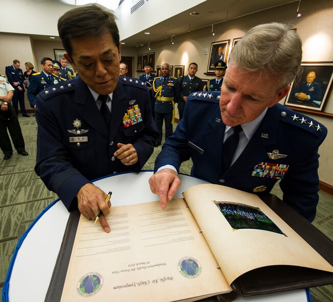 (From left) General Harukazo Saitoh, Japan Air Self-Defense Force chief of staff, signs the Pacific Air Forces guestbook alongside Gen. Hawk Carlisle, PACAF commander, at the Pacific Air Forces Headquarters building March 29, 2014, at Joint Base Pearl Harbor-Hickam, Hawaii. The goal of the symposium is to encourage increased cooperation, interoperability, and friendship while also helping promote peace and stability in the Pacific. (U.S. Air Force photo by Staff Sgt. Nathan Allen)