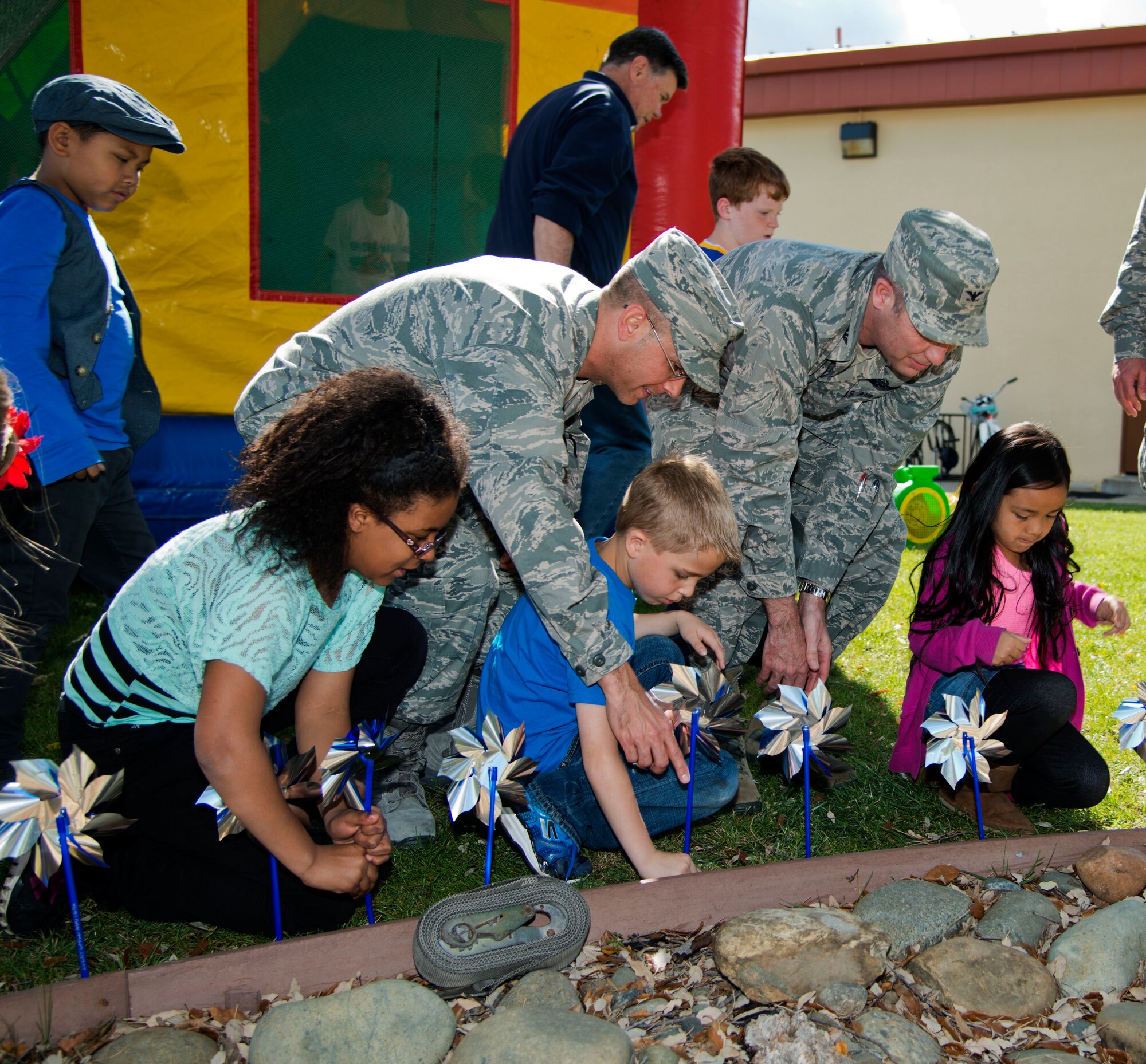 Col. Matthew Burger, 349th AMW commander, and Col. Mark MacDonald, 615th Contingency Operations Support Group commander and stand –in 615th Contingency Response Wing commander, help children from the Youth Center plant pinwheels in the pinwheel garden during the Family Fun Fest Wednesday.  The pinwheel garden raises awareness for child abuse month. Some communities use the pinwheels to represent the number of children affected by child abuse (U.S. Air Force photo/Senior Airman Nicole Leidholm)