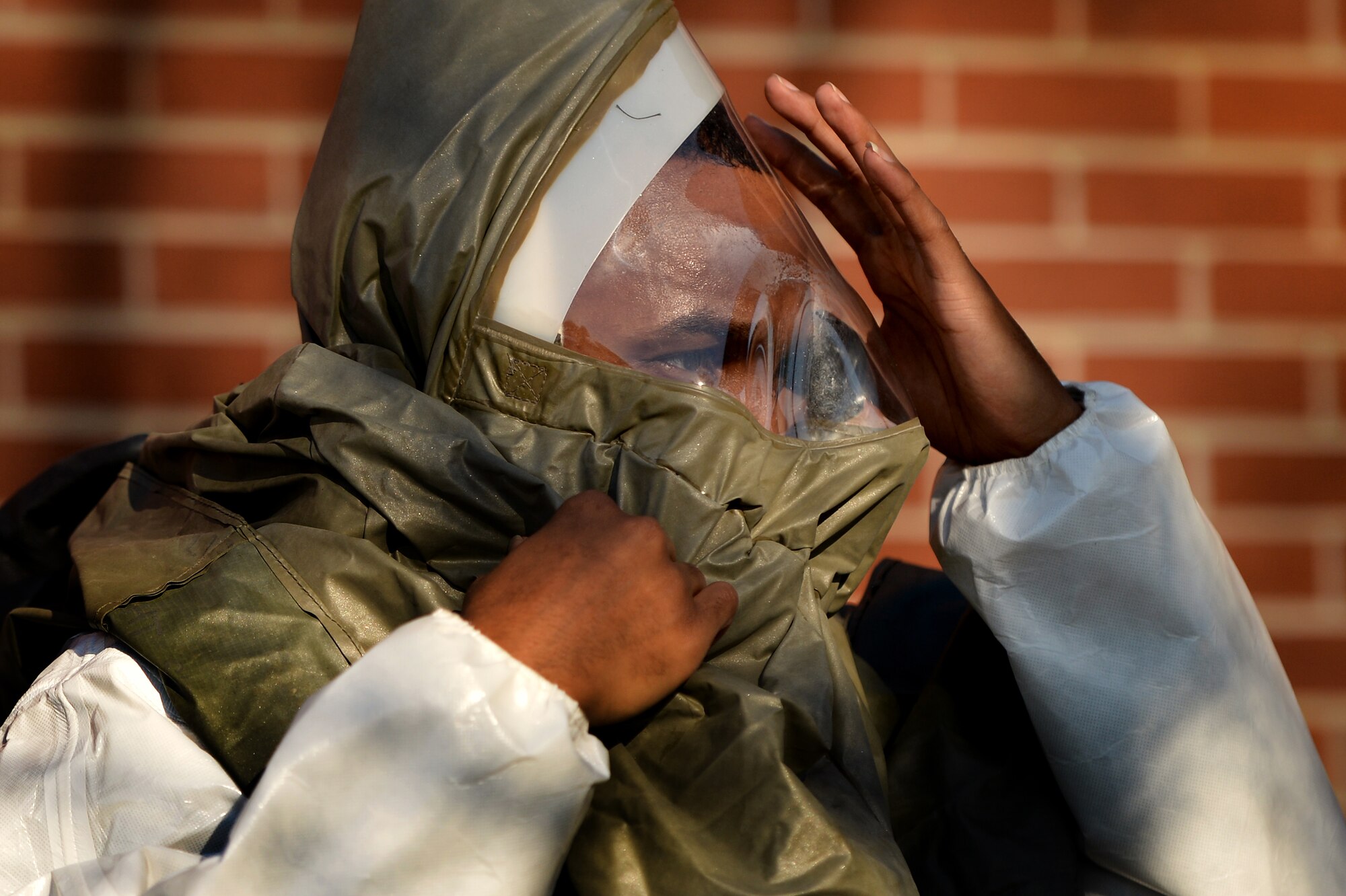 A U.S. Air Force Airman assigned to the 20th Medical Group quickly dons a decontamination suit as he responds to a chemical and biological incident during a Mass Accident Response Exercise, April 4, 2014, Shaw Air Force Base, S.C. Airmen who participated in the exercise set up an In Place Person Decontamination post where they processed and decontaminated affected patients. Exercise such as these keep 20th MDG Airmen training and prepared for real world situations. (U.S. Air Force photo by Staff Sgt. Kenny Holston/Released)