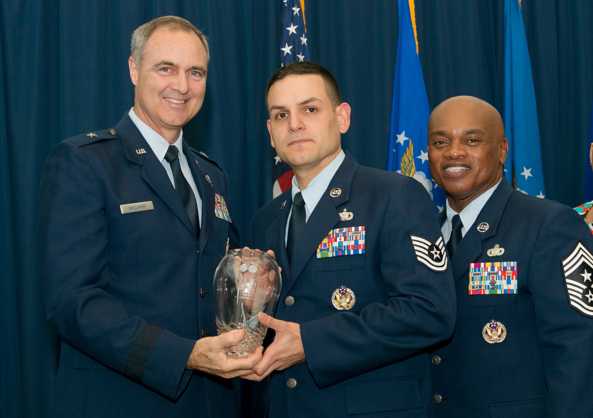Brig. Gen. R. Scott Williams, the commander of the Air National Guard Readiness Center, and Chief Master Sgt. Tony L. Whitehead, the command chief master sergeant of the ANGRC, present the Non-Commissioned Officer of the Year award to Tech. Sgt. Roberto Zayas-Ginorio, Logistics, during the ANGRC 2013 Annual Awards Ceremony April 4, 2014, at the ANGRC, Joint Base Andrews, Md. The ceremony hosted by Williams recognizes the accomplishments of the ANGRC staff. (U.S. Air National Guard photo by Master Sgt. Marvin R. Preston/RELEASED)