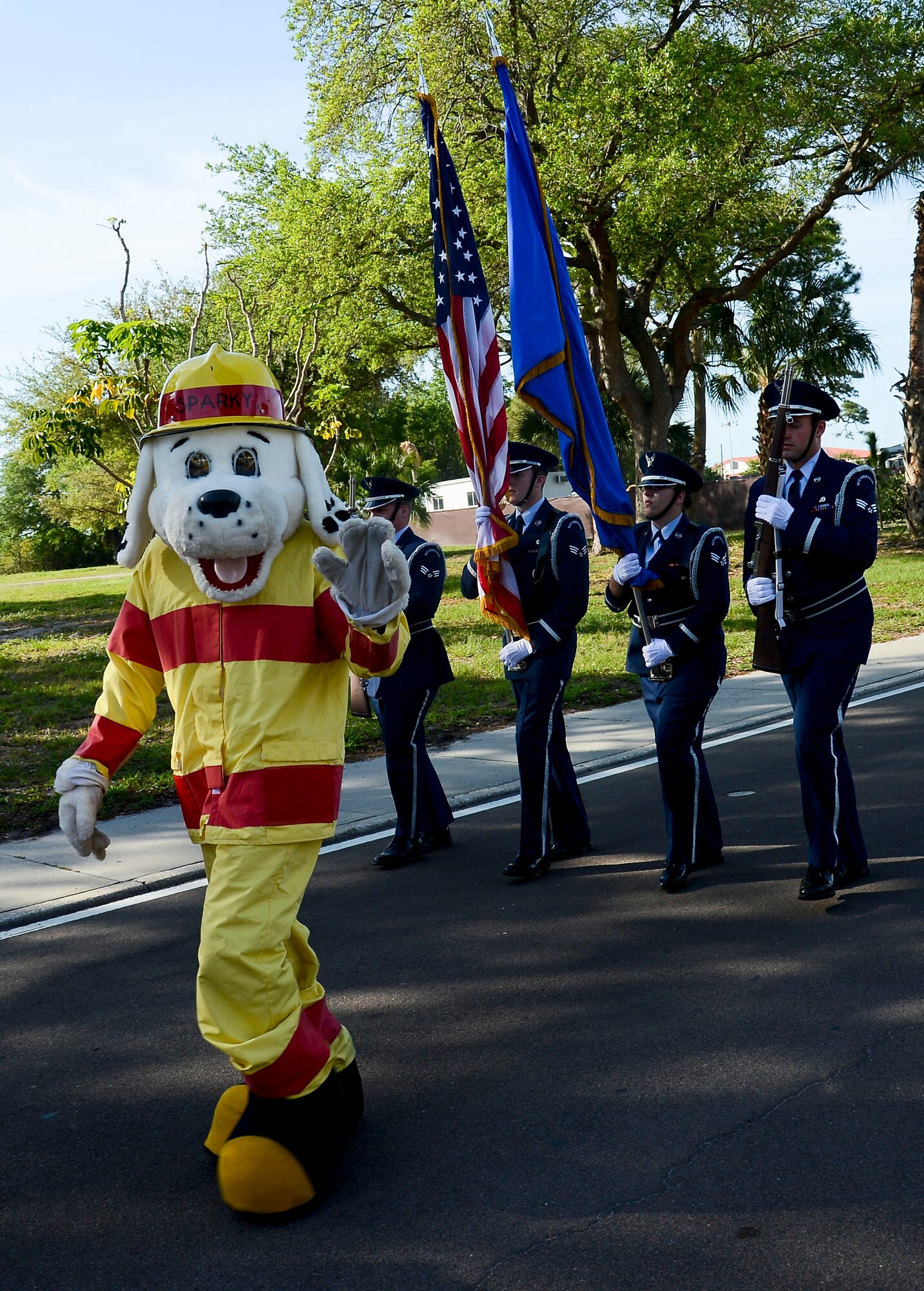 Sparky, the fire department mascot, and members from the base honor guard walk in the Month of the Military Child parade April 3, 2014 at MacDill Air Force Base, Fla. The parade featured members of the base honor guard, a drum line, Sparky the fire department mascot, and floats made by the staff of the Child Development CentersCDCs. (U.S. Air Force photo by Senior Airman Jenay Randolph/Released)