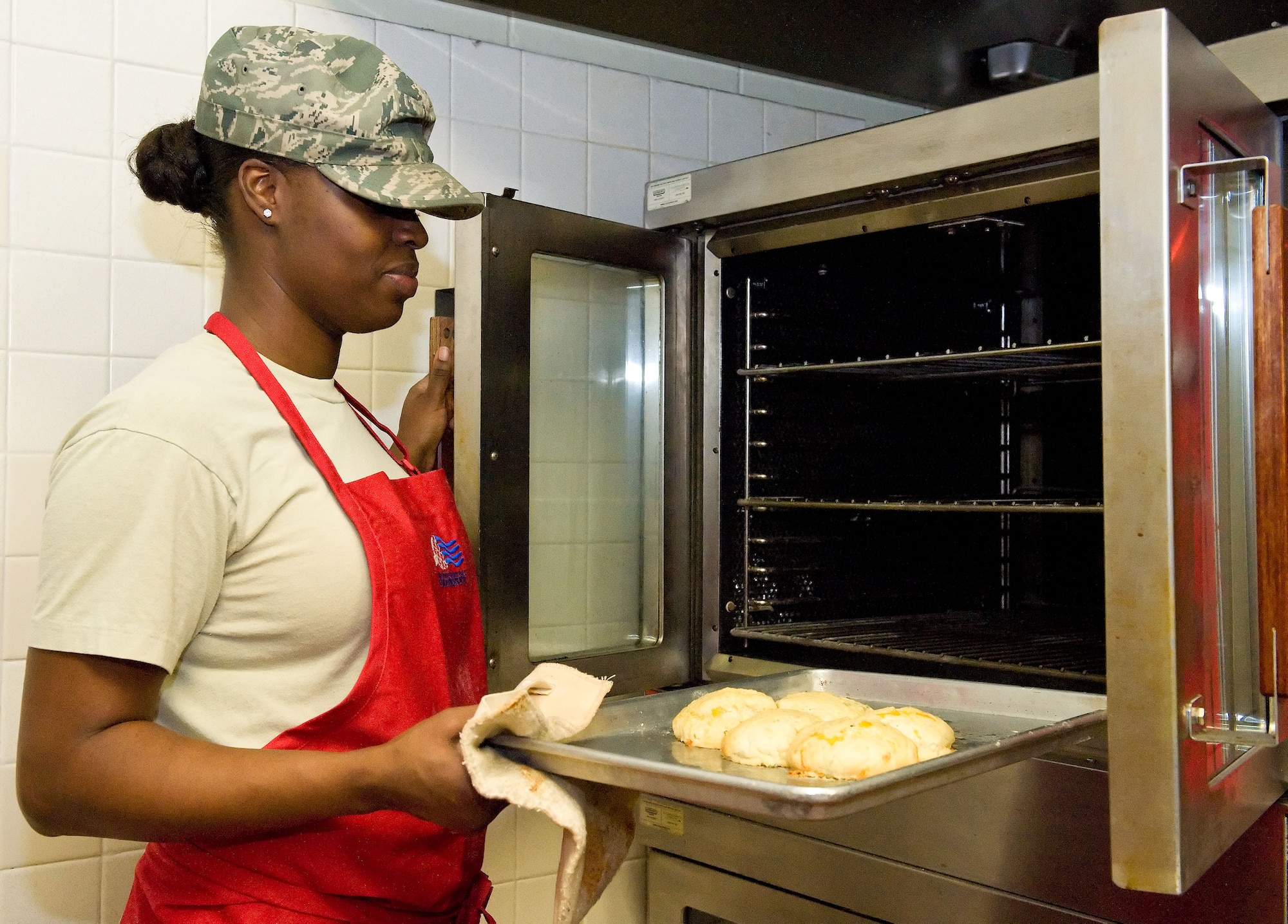 Tech. Sgt. Kenttrina Smith, 436th Force Support Squadron food service noncommissioned officer in charge, removes cheese biscuits from the oven April 2, 2014, at the Patterson Dining Facility on Dover Air Force Base, Del. Smith baked a test batch for 20 minutes prior to baking dozens of biscuits for Team Dover lunch hour snack line patrons. (U.S. Air Force photo/Roland Balik)