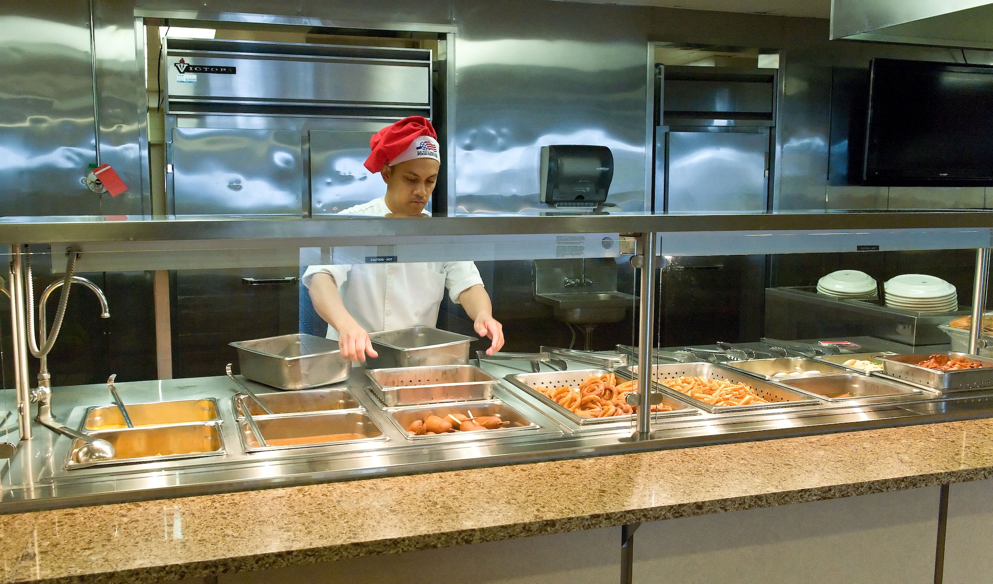 Staff Sgt. Rommel Ongaco, 436th Force Support Squadron food service supervisor, places a food tray on the snack line March 28, 2014, at the Patterson Dining Facility on Dover Air Force Base, Del. Food service personnel serve an average of 200-250 Team Dover lunch hour meal patrons on a daily basis during the week. (U.S. Air Force photo/Roland Balik)