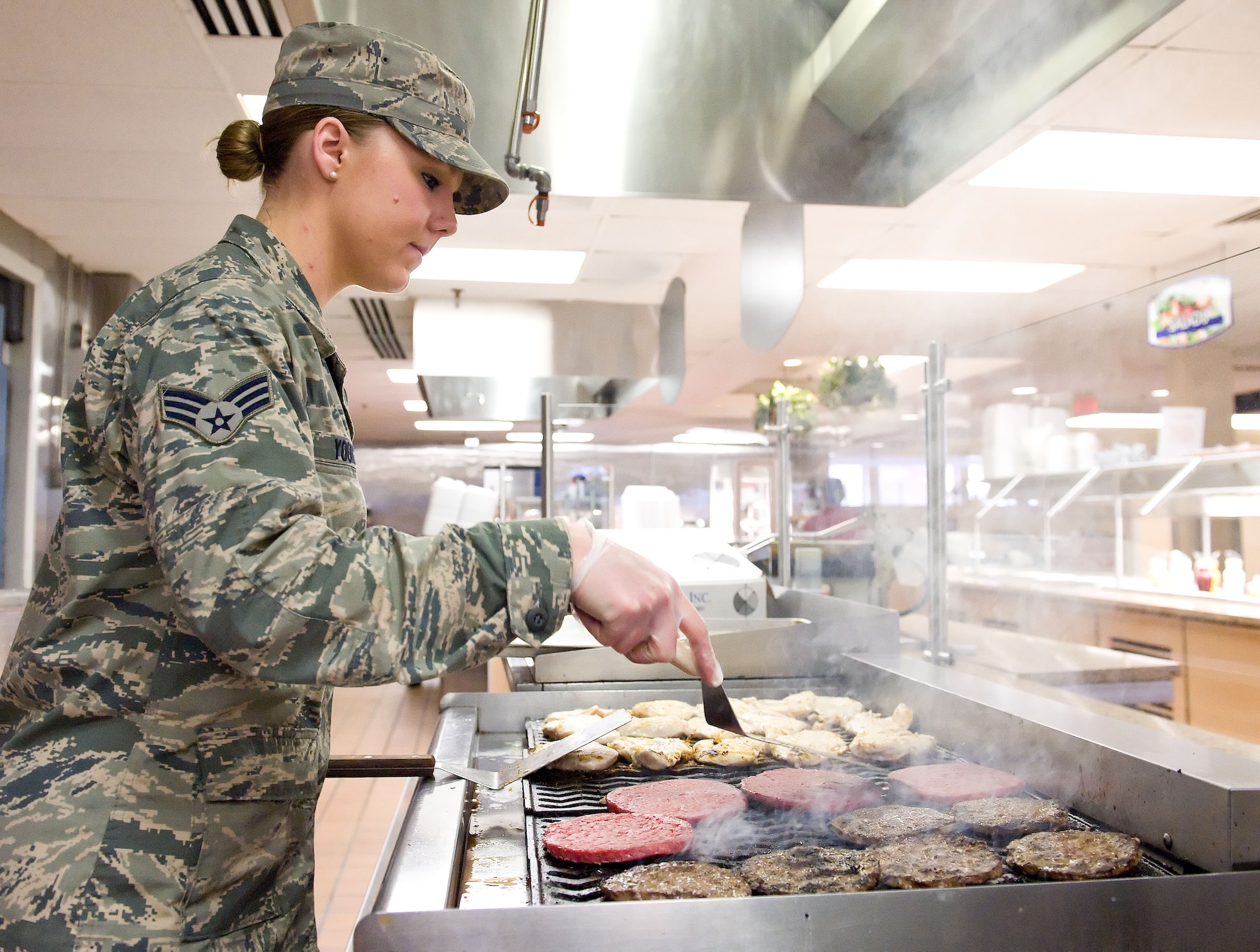 Senior Airman Katie Young, 436th Force Support Squadron food service apprentice, grills chicken and hamburger March 28, 2014, at the Patterson Dining Facility on Dover Air Force Base, Del. Young cooked approximately 150 chicken breasts and 80 hamburger patties for the lunch hour snack line. (U.S. Air Force photo/Roland Balik)