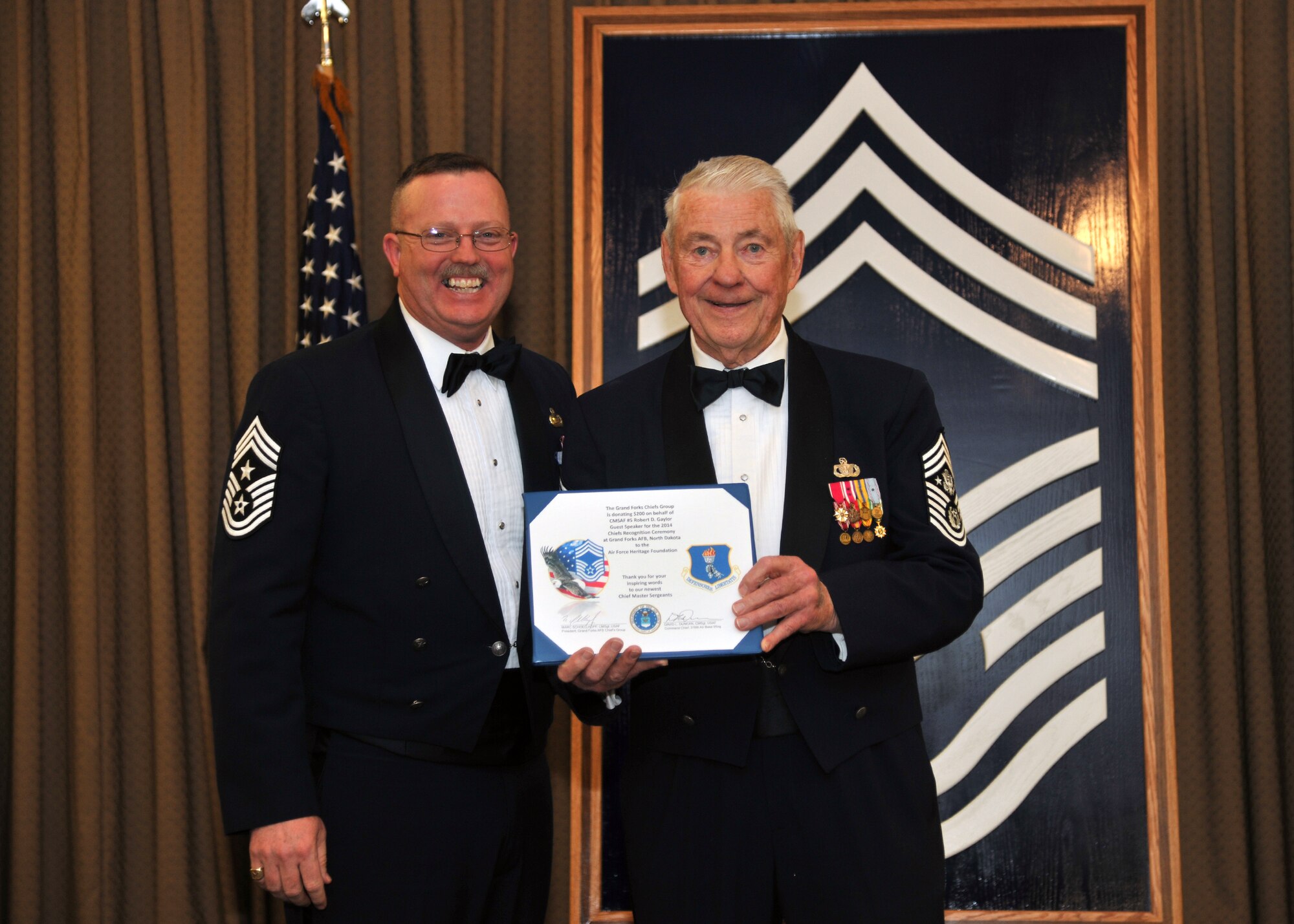 Chief Master Sgt. David Duncan, 319th Air Base Wing command chief (left) presents Retired Chief Master Sgt. Robert Gaylor, the fifth Chief Master Sergeant of the Air Force (right), with a donation of $200 on behalf of the Grand Forks AFB Chiefs’ Group for the Air Force Heritage Foundation on March 28, 2014, at the Northern Lights Club on Grand Forks Air Force Base, N.D. Gaylor was the guest speaker at this year's chiefs’ recognition ceremony, which celebrated the promotion of the base’s four newest chief master sergeants. (U.S. Air Force photo/Senior Airman Xavier Navarro)