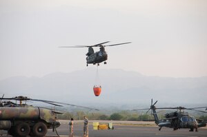 A U. S. Army CH-47 Chinook helicopter from the 1-228th Aviation Regiment takes off from Soto Cano Air Base, Honduras with a Bambi Bucket attached to fight a fire on a mountain ridge in Comayagua, Honduras.  The fire posed a threat to destroy homes and to cut off an access road to a local village.  Within one hour of receiving the call, the helicopters dumped about 6,180 gallons of water on the blaze to alleviate the danger.  (Photo by U. S. Air National Guard Capt. Steven Stubbs)