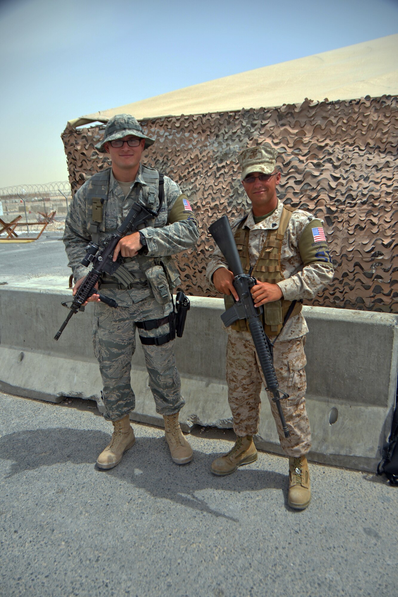 Senior Airman Colby Davis and Marine Sgt. Dominic Byron pose for a photo at Al Udeid Air Base, Qatar, April 2, 2014. Airmen of the 379th Expeditionary Security Forces Squadron have teamed up with Marines from the Tactical Electronic Warfare Squadron 3 for one mission; flightline security. Byron is an aviation electrician who works on EA-6B Prowlers, deployed from Cherry Point Marine Corps Air Station, N.C., and a New Milford, Conn., native. Davis is a 379th SFS defender who is deployed from Joint Base Elmendorf-Richardson, Alaska, and a Brooksville, Ky., native. (U.S. Air Force photo/Senior Airman Jared Trimarchi) 
