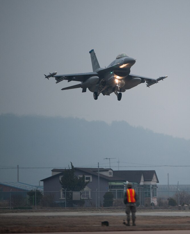 An 8th Security Forces Airman stands guard as a 35th Fighter Squadron F-16 prepares to land on the Alternate Landing Surface at Kunsan Air Base, Republic of Korea, Mar. 19, 2014. The ALS was activated and utilized to test the Wolf Pack's ability to land aircraft in the event that the primary runway is unavailable. (U.S. Air Force photo by Staff Sgt. Clayton Lenhardt/Released)
