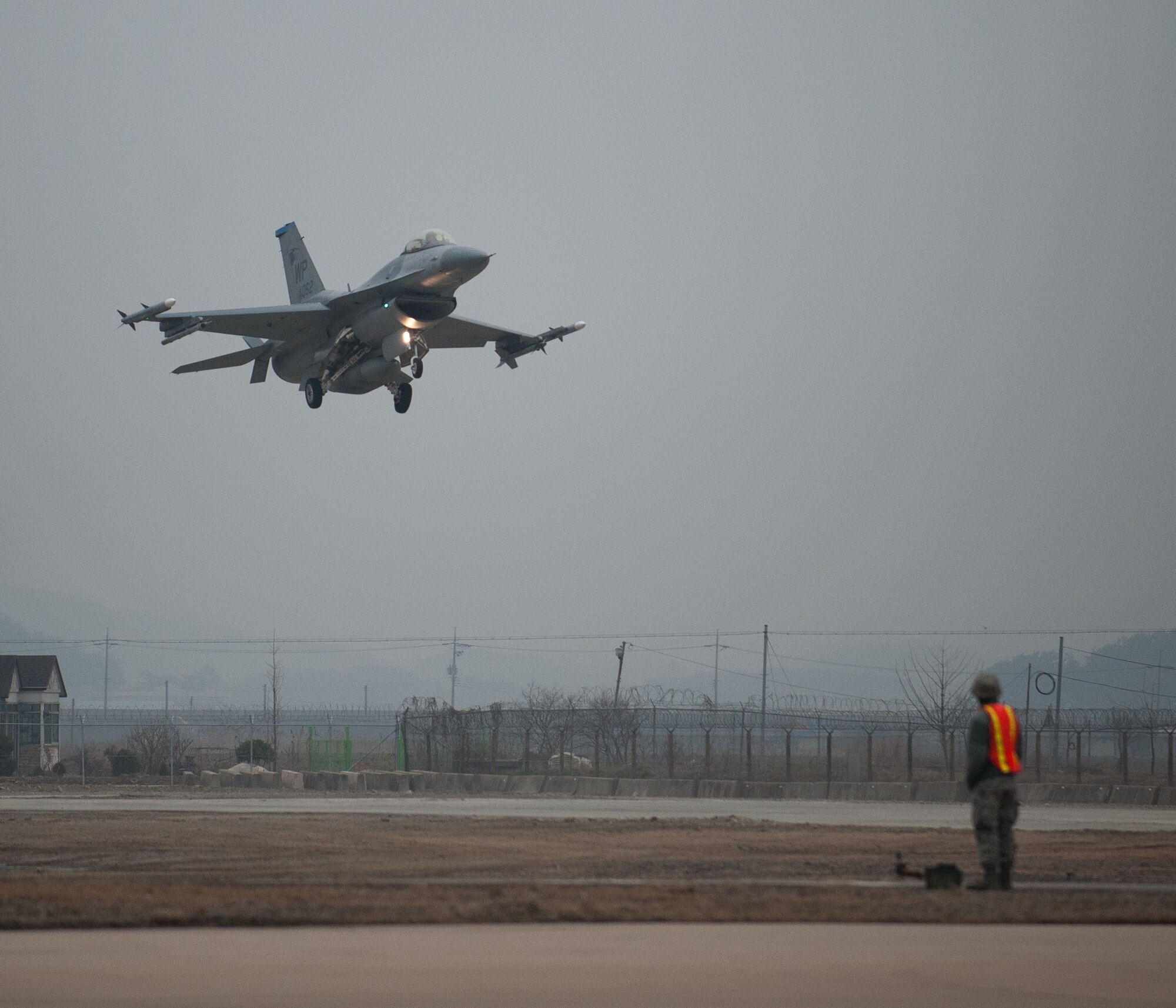 An 8th Security Forces Airman stands guard as a 35th Fighter Squadron F-16 prepares to land on the Alternate Landing Surface at Kunsan Air Base, Republic of Korea, Mar. 19, 2014. The ALS was activated and utilized to test the Wolf Pack's ability to land aircraft in the event that the primary runway is unavailable. (U.S. Air Force photo by Staff Sgt. Clayton Lenhardt/Released)