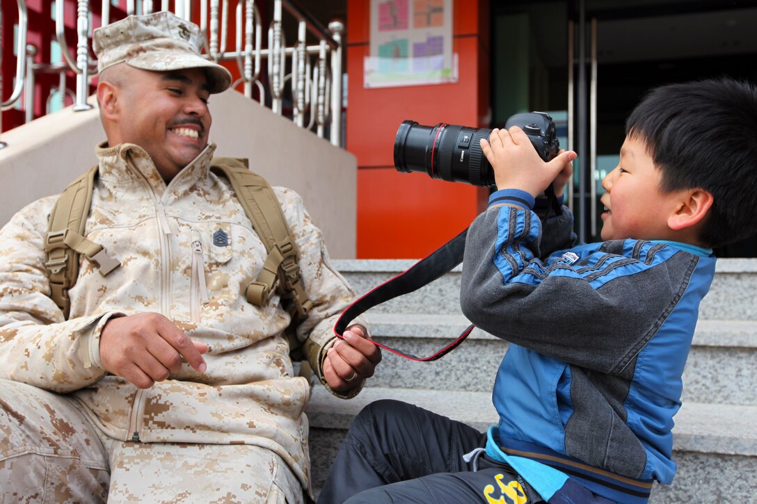 A boy from the Pohang Orphanage uses the camera of Gunnery Sgt. Ismael Pena, combat camera chief for the Command Element, 31st Marine Expeditionary Unit, and a native of Yakima, Wash., during a visit by 24 Marines and Sailors here, April 5. The Pohang orphanage was founded after the Korean War in 1953 by a Navy chaplain from the 1st Marine Air Wing. In 1954, the Navy Seabees constructed the original building. Since then, the children taken in by the orphanage have known regular visits from their camouflaged friends. The visit comes at the conclusion of the 31st MEU’s participation in Exercise Ssang Yong 2014, a bilateral training event that is a tribute to the maturity of the US-ROK relationship. 