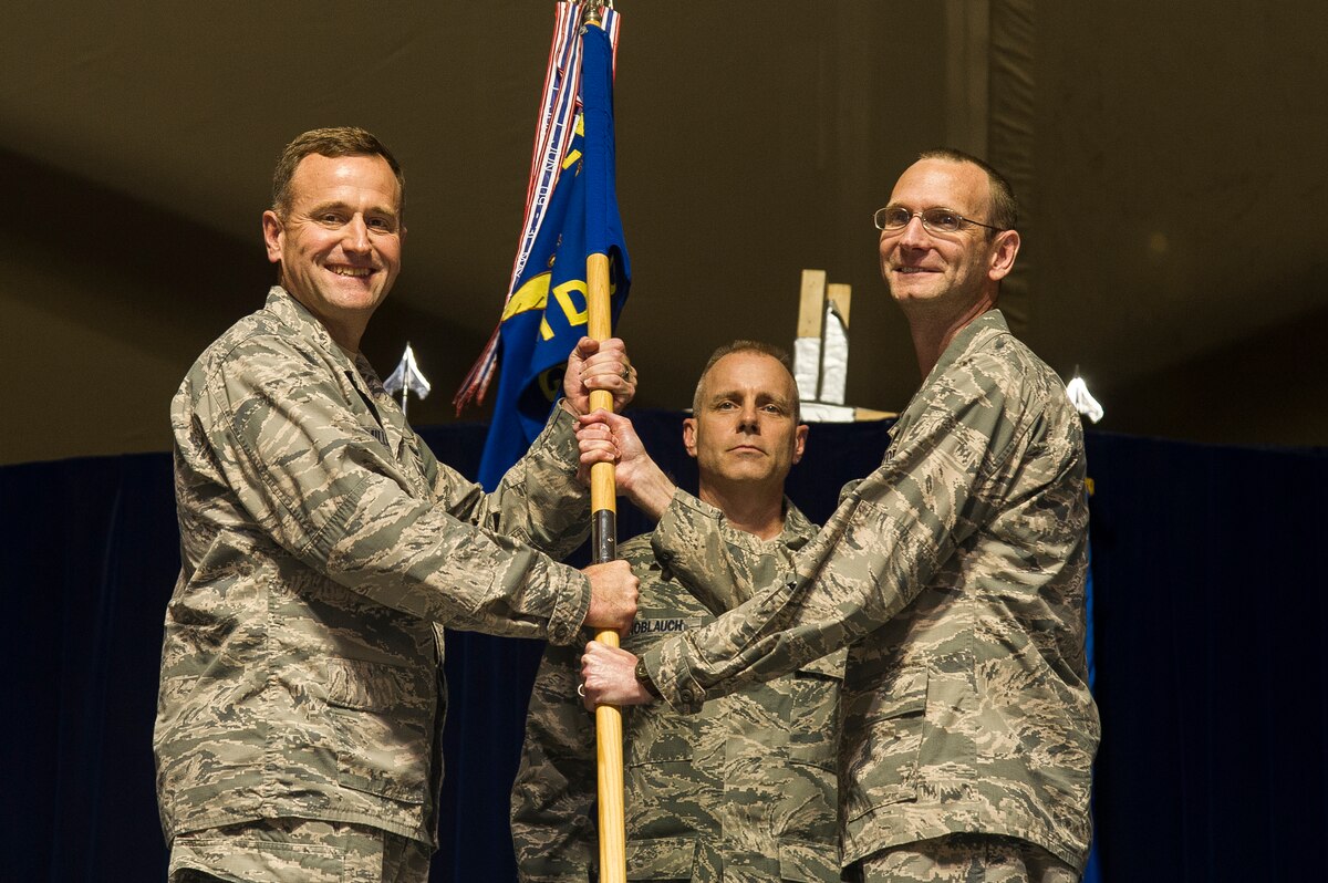 Col. James Knowles, 376th Expeditionary Medical Group commander, hands the 376th EMDG guide-on to Col. John Millard, 376th Air Expeditionary Wing commander, during the group’s inactivation ceremony at Transit Center at Manas, Kyrgyzstan, April 05, 2014. The 376th EMDG provided routine, urgent and emergency care to anyone who walked through their doors. In 2013, the 376th EMDG cared for more than 12,700 patients, responded to 85 ambulatory requests, tended for 23 military working dogs and assisted with 87 aeromedical evacuations. (U.S. Air Force photo/Senior Airman George Goslin)