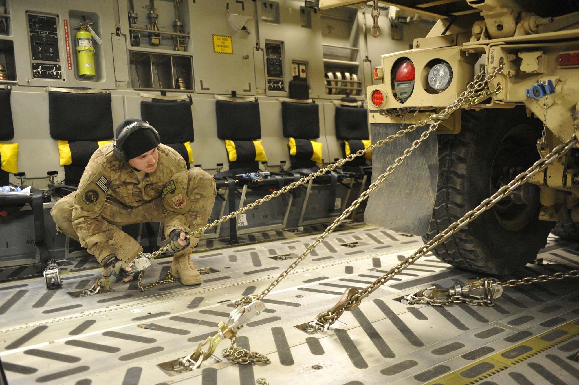 :  U.S. Air Force Senior Airman Brandon Reid, Air Terminal Operations Center representative, double-checks a chain binder securing an armored dump truck in the back of a C-17 Globemaster III aircraft at Shindand Airfield, Afghanistan, March 10, 2014. Reid is part of a team responsible for loading cargo, vehicles and passengers at Shindand.(U.S. Air Force photo by Senior Master Sgt. Gary J. Rihn/Released)