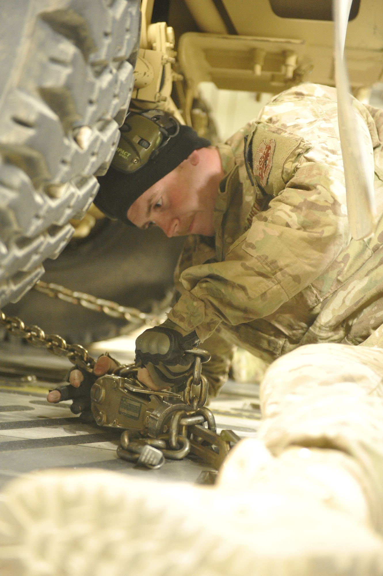 U.S. Air Force Senior Airman Brandon Reid, Air Terminal Operations Center representative, uses a chain binder to secure a vehicle being flown out of Shindand Airfield, Afghanistan, in the back of a C-17 Globemaster III aircraft, March 10, 2014. Reid is part of a team responsible for loading cargo, vehicles and passengers at Shindand.(U.S. Air Force photo by Senior Master Sgt. Gary J. Rihn/Released)
