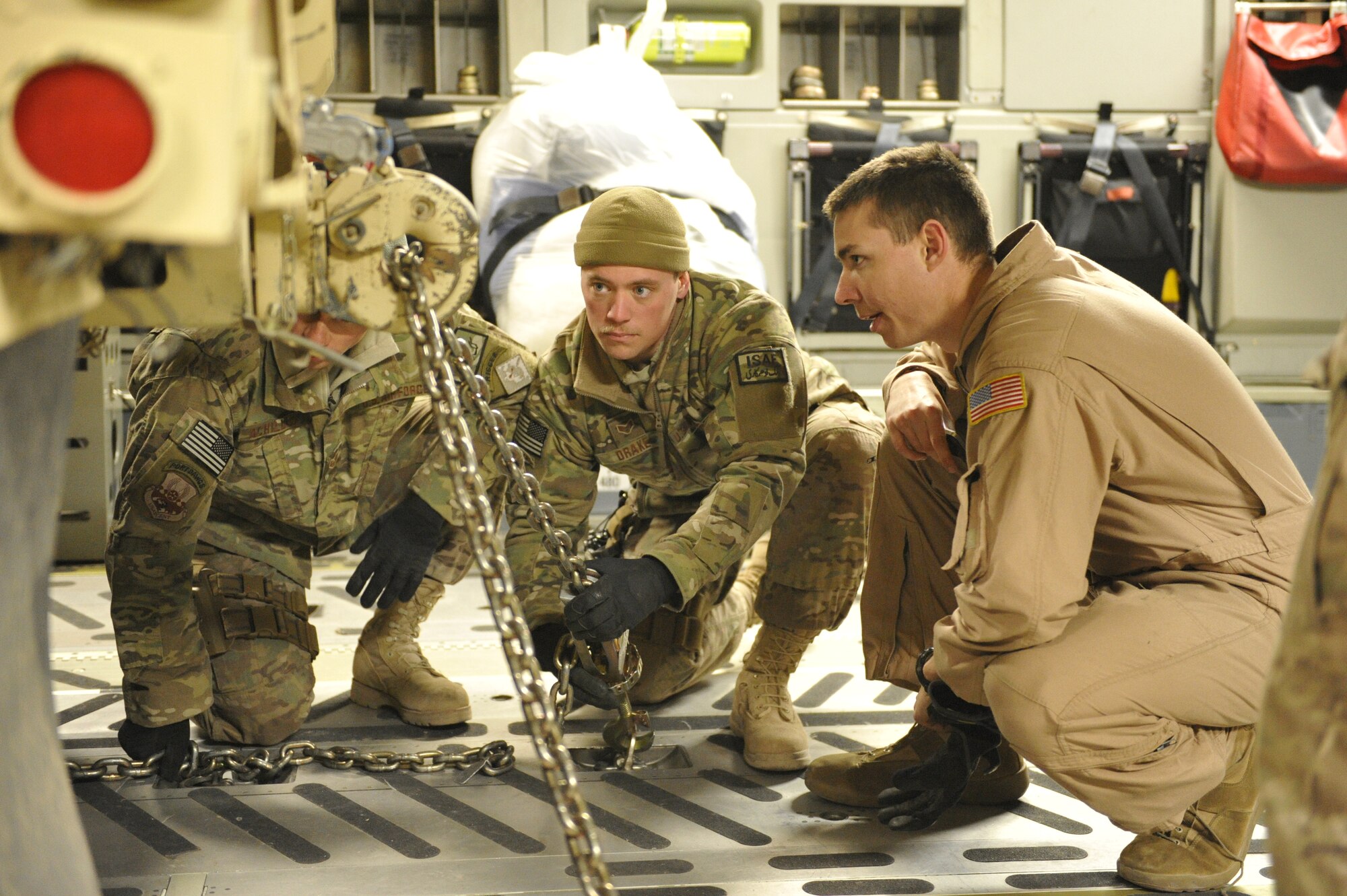 U.S. Air Force Staff Sgt. Henry Achilles, Senior Airman Joshua Drake and Senior Airman Devin Lynch chain down an armored dump truck that is being flown out of Shindand Airfield, Afghanistan, in the back of a C-17 Globemaster III aircraft, March 10, 2014. The dump truck was being moved for use at another location.(U.S. Air Force photo by Senior Master Sgt. Gary J. Rihn/Released) 