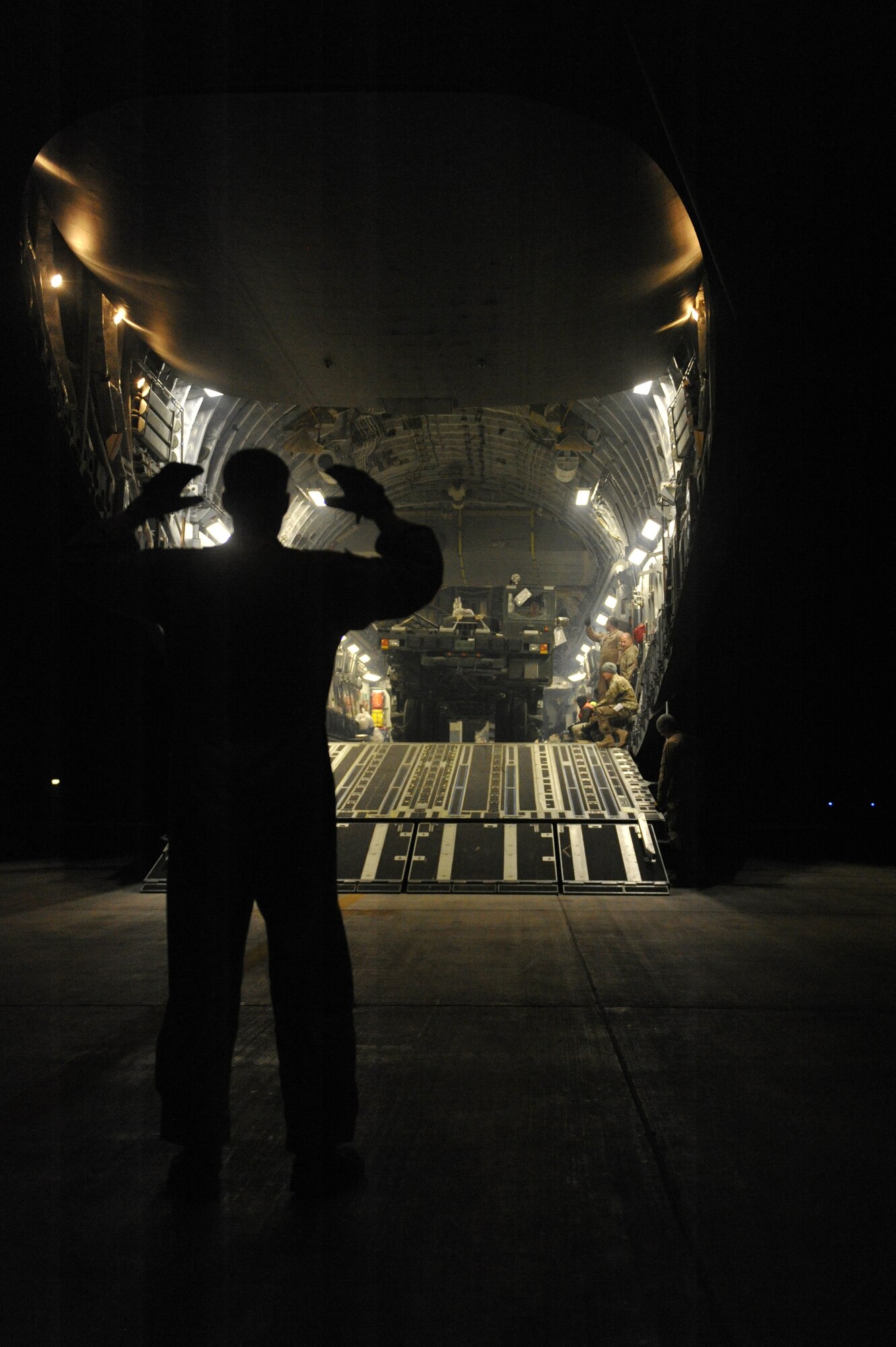 U.S. Air Force Senior Airman Senior Airman Devin Lynch, C-17 Globemaster loadmaster,  marshals a new 60 ton cargo loader down the ramp of a C-17 Globemaster III at Shindand Airfield, Afghanistan, March 10, 2014. The loader had just arrived on the C-17, and is destined to be used for loading and unloading cargo at Shindand.(U.S. Air Force photo by Senior Master Sgt. Gary J. Rihn/Released)    