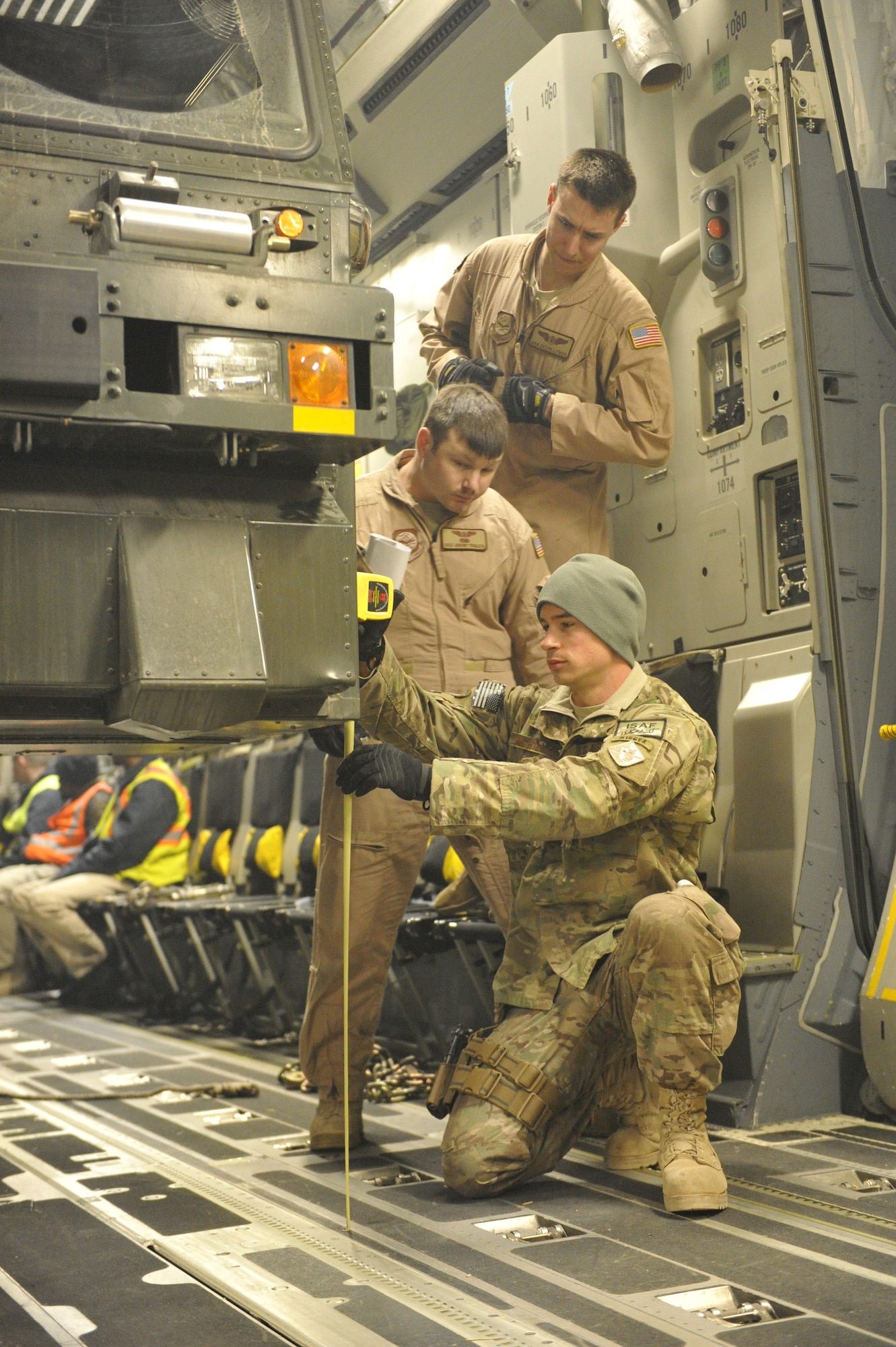 U.S. Air Force Staff Sgt. Henry Achilles, Air Terminal Operations Center non-commissioned officer in charge, verifies with the C-17 Globemaster III loadmasters that there is sufficient clearance to drive a new 60 ton cargo loader down the C-17’s ramp at Shindand Airfield, Afghanistan, March 10, 2014. The loader had just arrived on the C-17, and is destined to be used for loading and unloading cargo at Shindand.(U.S. Air Force photo by Senior Master Sgt. Gary J. Rihn/Released)    