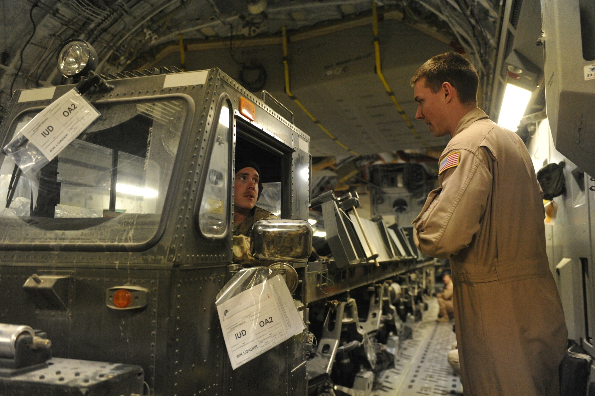 U.S. Air Force Senior Airman Brandon Reid, Air Terminal Operations Center representative, confers with Senior Airman Devin Lynch, C-17 Globemaster III loadmaster, before driving a new 60 ton cargo loader out of the back of a C-17 aircraft at Shindand Airfield, Afghanistan, March 10, 2014. The new cargo loader will be used for moving cargo on and off of aircraft at Shindand.(U.S. Air Force photo by Senior Master Sgt. Gary J. Rihn/Released)