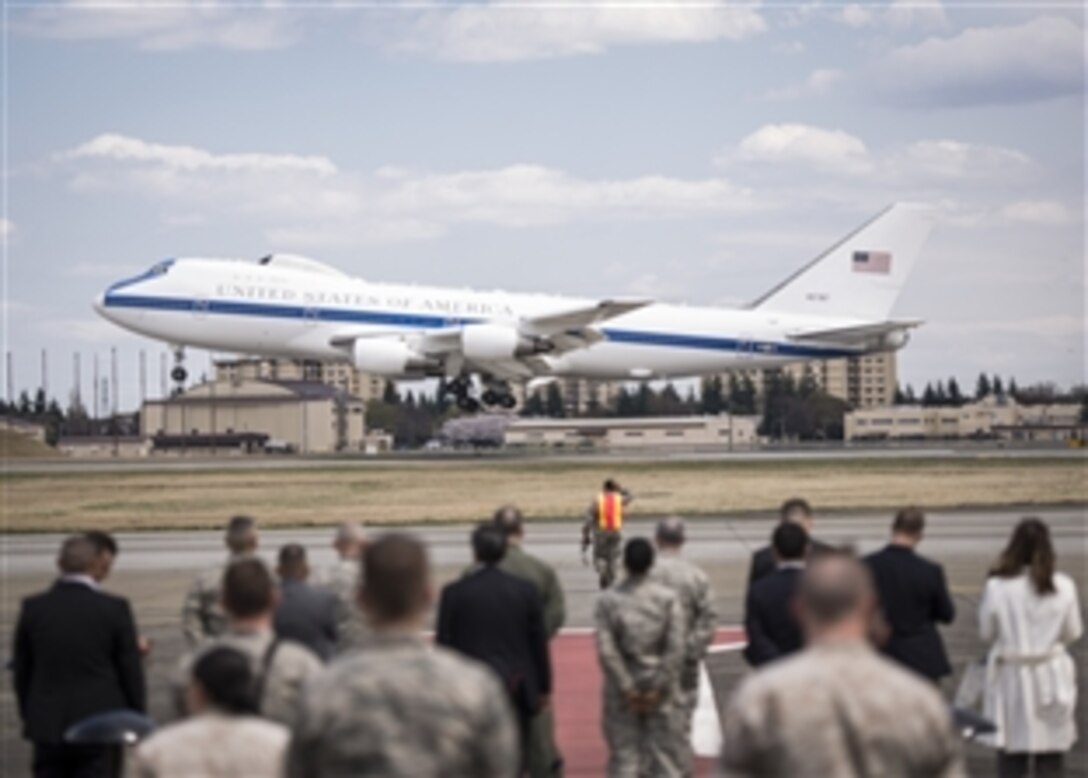 Leaders watch as a U.S. military aircraft carrying U.S. Defense Secretary Chuck Hagel lands on Yokota Air Base, Japan, April 5, 2014. Hagel traveled from Hawaii to the base during his forth visit to the Asia-Pacific region.