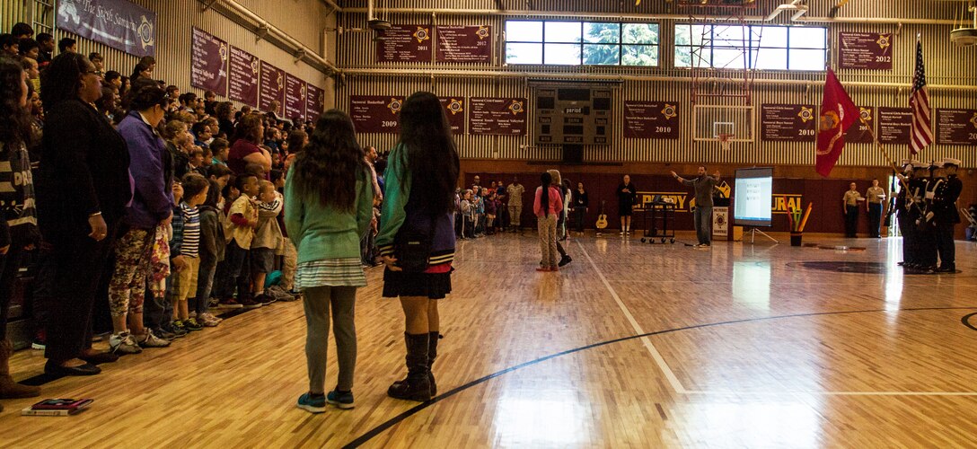 Attendees of a uniform parade stand for the marching of the colors inside the Matthew C. Perry High School gymnasium aboard Marine Corps Air Station Iwakuni, Japan, April 3, 2014. Volunteers donned past and present Marine Corps uniforms for the event, which took place in conjunction with Month of the Military Child; recognizing the children of parents in the U.S. military.