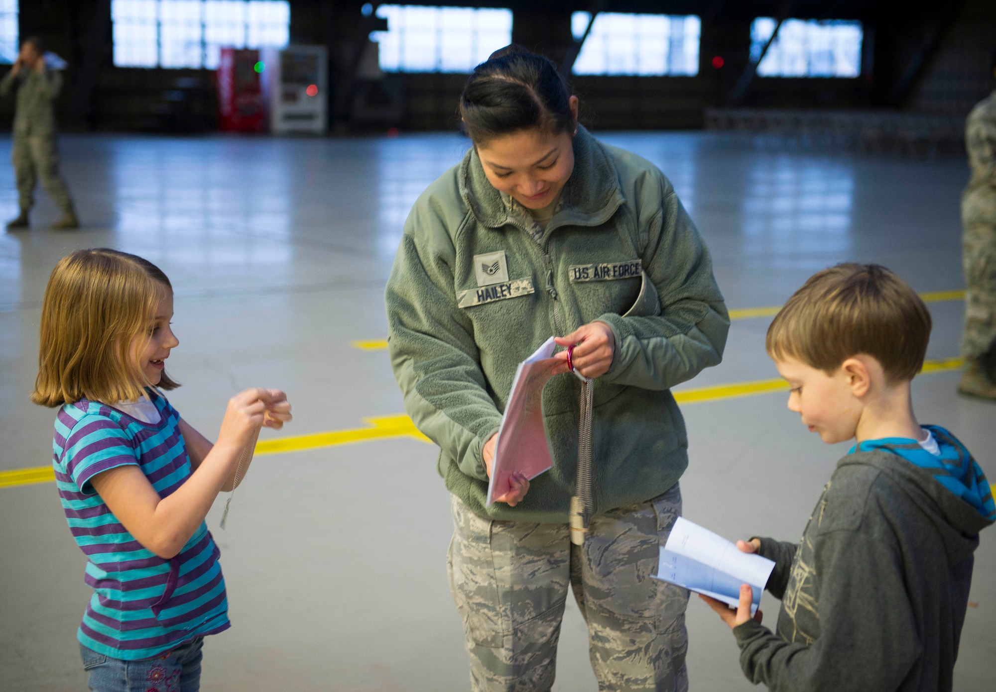 Staff Sgt. Kristina Hailey, Kids Understanding Deployment Operations Support volunteer, helps children find their chalk assignments and passes out dog tags on day one April 3, 2014 at Yokota Air Base, Japan. KUDOS allows children to experience the deployment process and gain insight into how their parents live and work while deployed. (U.S. Air Force photo by Staff Sgt. Chad C. Strohmeyer/Released)