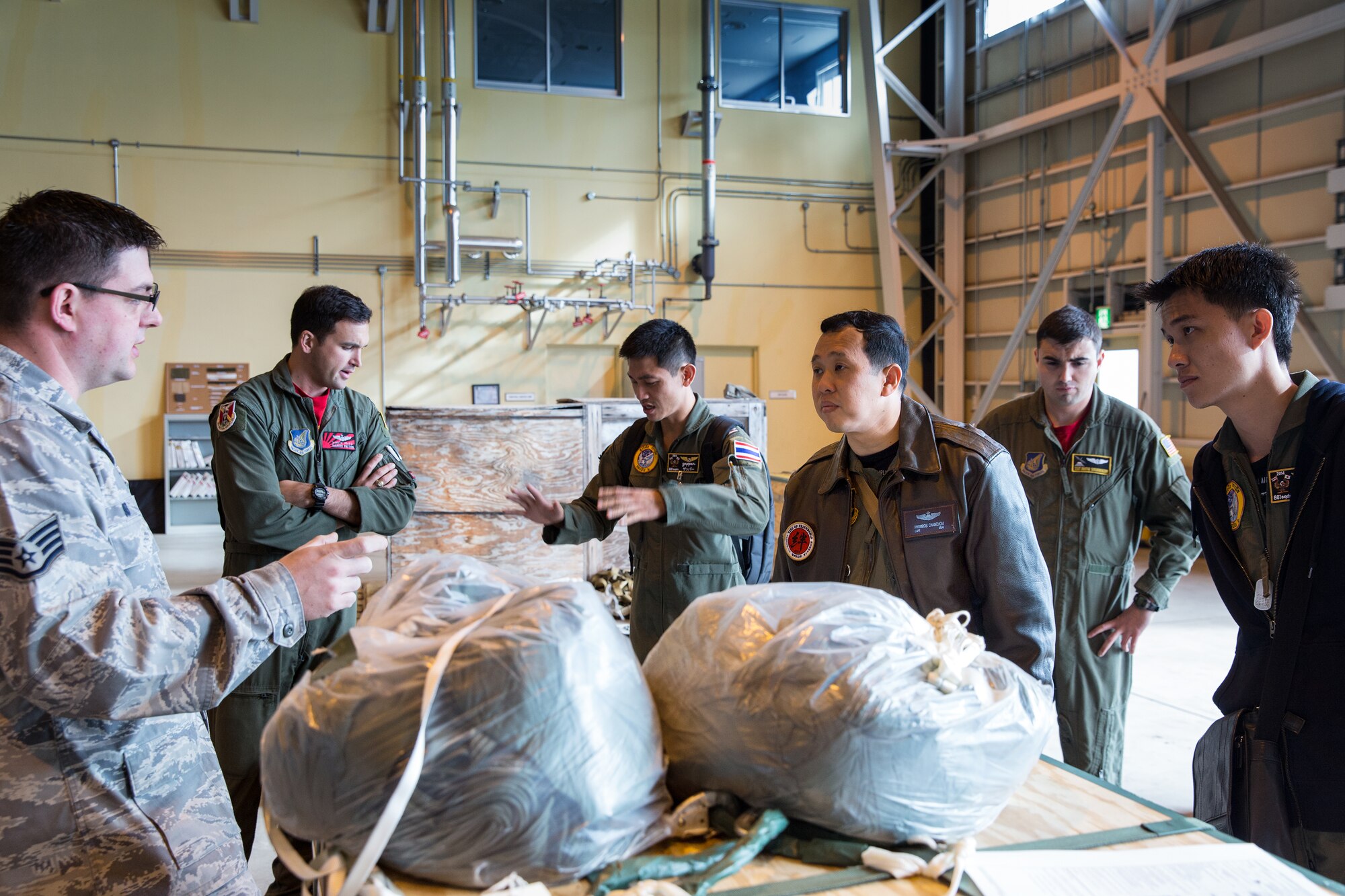 U.S. Air Force Staff Sgt. Landon Soles (left), 374th Logistics Readiness Squadron combat mobility flight, explains a Low-Cost, Low-Altitude bundle to members from the Royal Thai Air Force in the 374th Combat Mobility Flight at Yokota Air Base, Japan, April 4, 2014. Members of the Royal Thai Air Force visited Yokota for an annual mission of the UNC-R, a tenant unit at Yokota. (U.S. Air Force photo by Osakabe Yasuo/Released)