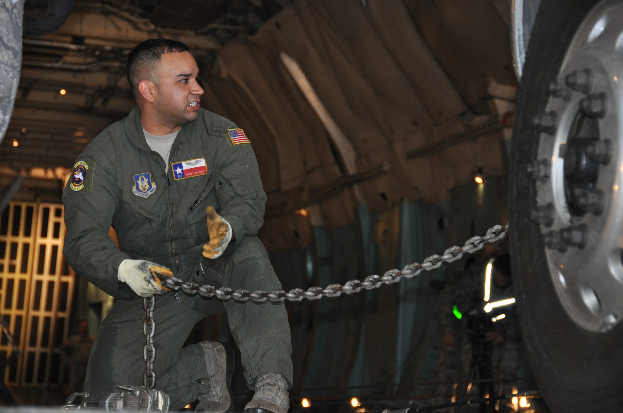 Senior Airman Christian Ingle, a 68th Airlift Squadron loadmaster, adjusts a chain to secure a vehicle from Army North's Task Force-51 on April 6, 2014 at Joint Base San Antonio-Lackland, Texas.  Soldiers learned how to load, document, weigh and measure their vehicles from 74th Aerial Port Squadron aerial porters. (U.S. Air Force photo by Tech Sgt. Carlos J. Trevino)