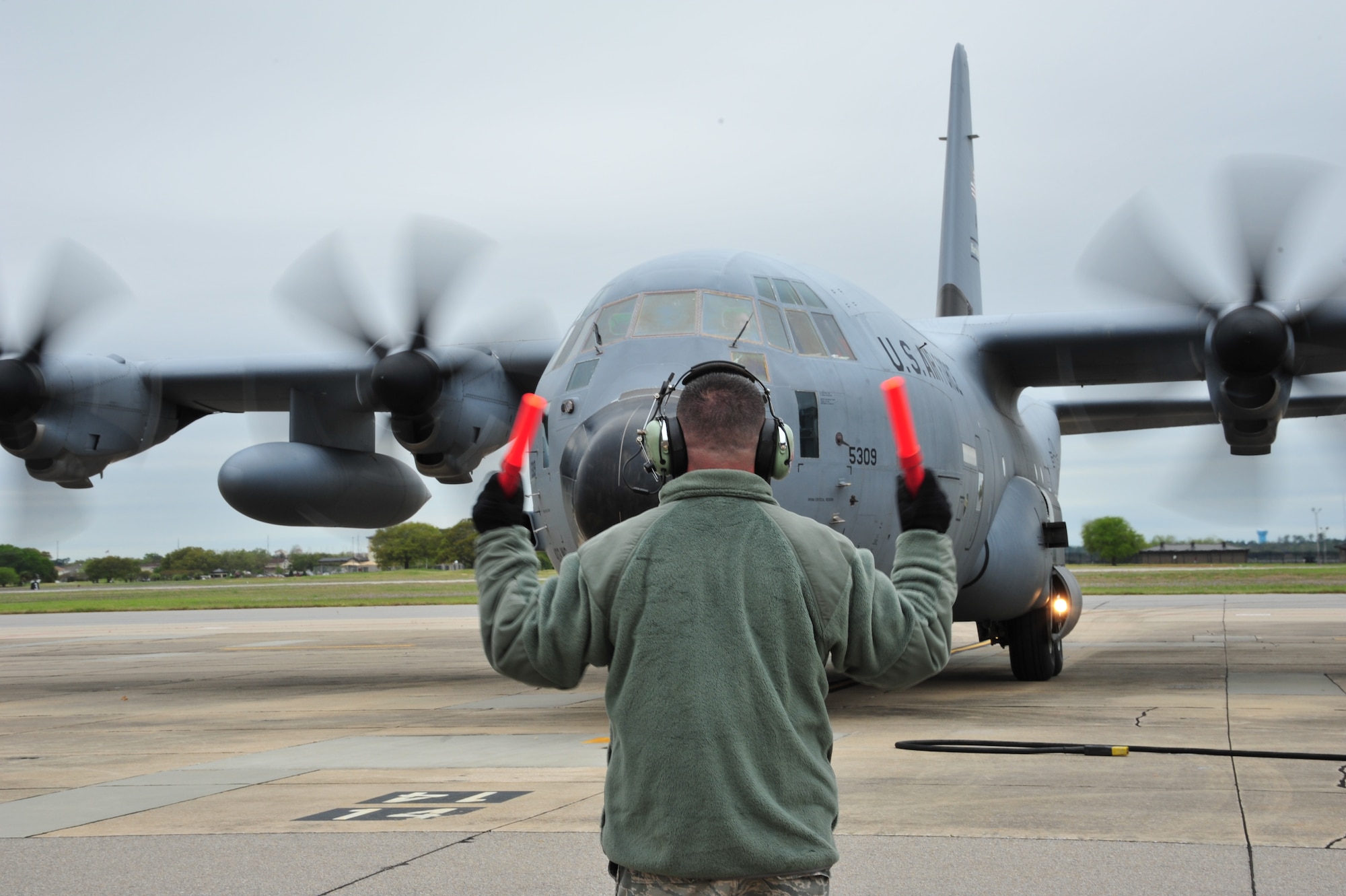 A Citizen Airman from the 403rd Wing guides aircrew on a WC-130J aircraft to their parking spot after returning from their flight here April 5, 2014.  The WC-130J aircraft was one of sixteen aircraft from the 403rd Wing to participate in Operation Surge Capacity, a large scale training exercise designed to test the 403rd Wing's ability to launch and recover a large formation of aircraft and to execute airdrops. (U.S. Air Force photo/Tech. Sgt. Ryan Labadens)