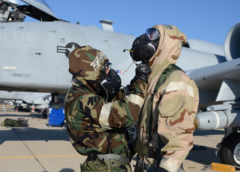 U.S. Air Force Airman 1st Class Ian Bollinger, a crew chief assigned to the 175th Aircraft Maintenance Squadron, Maryland Air National Guard, assists U.S. Air Force Staff Sgt. Noah Thomas, a crew chief assigned to the 175th Aircraft Maintenance Squadron, Maryland Air National Guard, with donning his protective mask during a simulated chemical attack at Warfield Air National Guard Base, Baltimore, Md. on April 5, 2014. (U.S. Air National Guard photo by Tech. Sgt. Christopher Schepers/RELEASED)