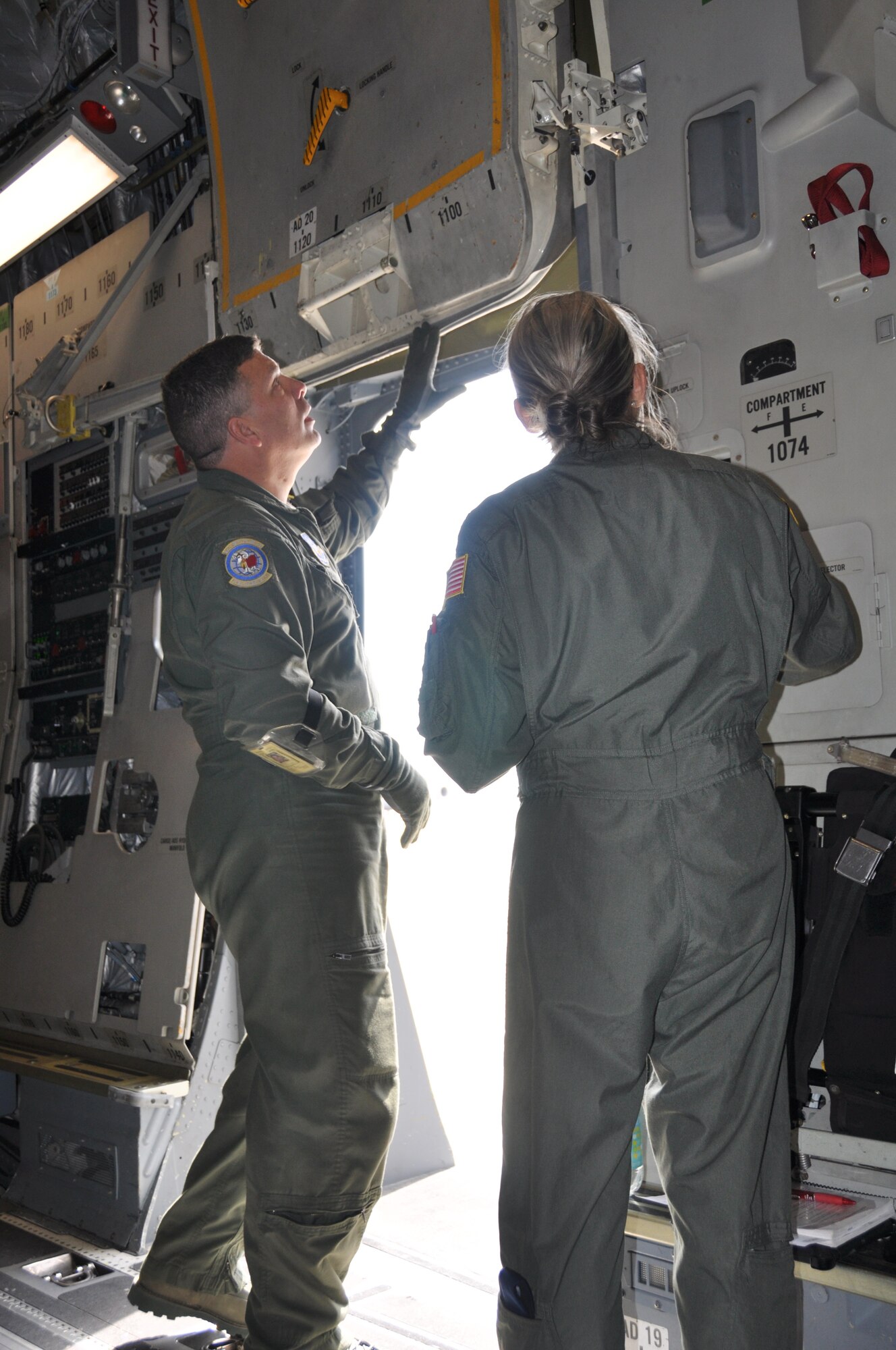 Senior Master Sgt. Michael Kent, 732nd Airlift Squadron loadmaster scheduler, conducts egress training with Lt. Col. Elizabeth Costanza, 514th Aeromedical Evacuation Squadron flight instructor student, by demonstrating emergency escape procedures on the door of a C-17 Globemaster III aircraft here April 5. Aircrew members undergo refresher egress courses every three years to satisfy training requirements (U.S. Air Force photo/Senior Airman Chelsea Smith).