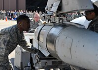 Weapons load crew members from the 36th Aircraft Maintenance Unit place a bomb on their team’s F-16 Fighting Falcon during a quarterly weapons load crew competition at Osan Air Base, Republic of Korea, April 4, 2014. During a weapons load crew competition, each member has a set of tasks to carry out and must work on a team of three or four, depending on the aircraft they are responsible for. (U.S. Air Force photo/Senior Airman Siuta B. Ika)