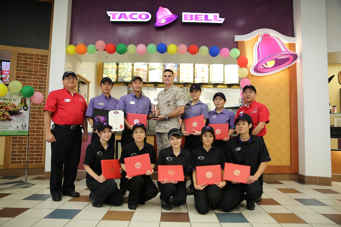 Employees of the Camp Hansen Exchange Taco Bell pose with Col. Stephen B. Lewallen, center, after being awarded the YUM Champions Club Award April 3. The award was given for outstanding food service in the Asia-Pacific region during 2013. Each year, all Taco Bells operated by the Exchange Services in the Asia-Pacific region are evaluated at random on their quality of food and customer service. This is the second time the Hansen Taco Bell has received the award after their first one in 2011. Lewallen is the commanding officer of III Marine Expeditionary Force Headquarters Group, III MEF, and the Camp Hansen commander. 