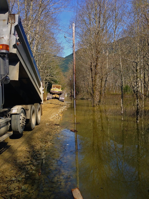 Employees with contractor Penny Lee, based out of Arlington, operate a dump truck and a D-5 bulldozer to push, smooth and compact material in 18 inches of water where the U.S. Army Corps of Engineers, Seattle District, is assisting Snohomish County with construction of a temporary berm to reduce flood impacts and prevent near-term flooding of SR 530 near mile post 37 at C Post Road.  Searchers have ongoing and planned recovery activities in this area after a March 22 mudslide constricted flow of the Stillaguamish River and caused flooding upstream.  Construction began today and the initial pass will be to match the water surface elevation with rock and embankment material and try to connect to high ground with the intention of raising it to elevation of SR530 at the berm’s completion in a week or so.  