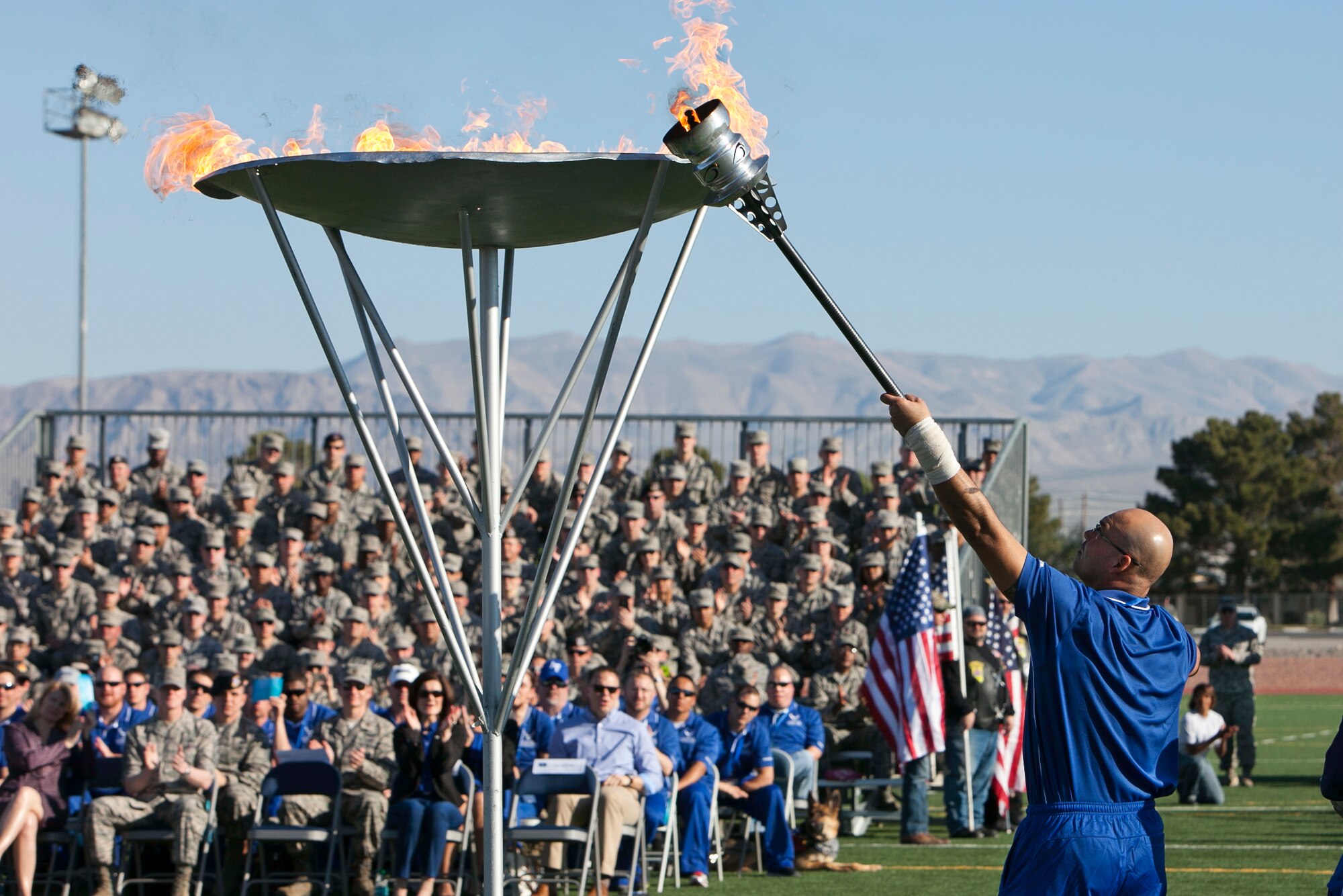 Master Sgt. Christopher Aguilera, an Air Force Wounded Warrior participant lights the cauldron signifying the beginning of the Air Force Wounded Warrior Trails April 7, 2014, at Nellis Air Force Base, Nev.  Aguilera, who is a survivor of the June 9, 2010 “Pedro 66” helicopter crash in southwest Afghanistan, will participate in in seven events during the trials. (U.S. Air Force Photo by Lorenz Crespo)