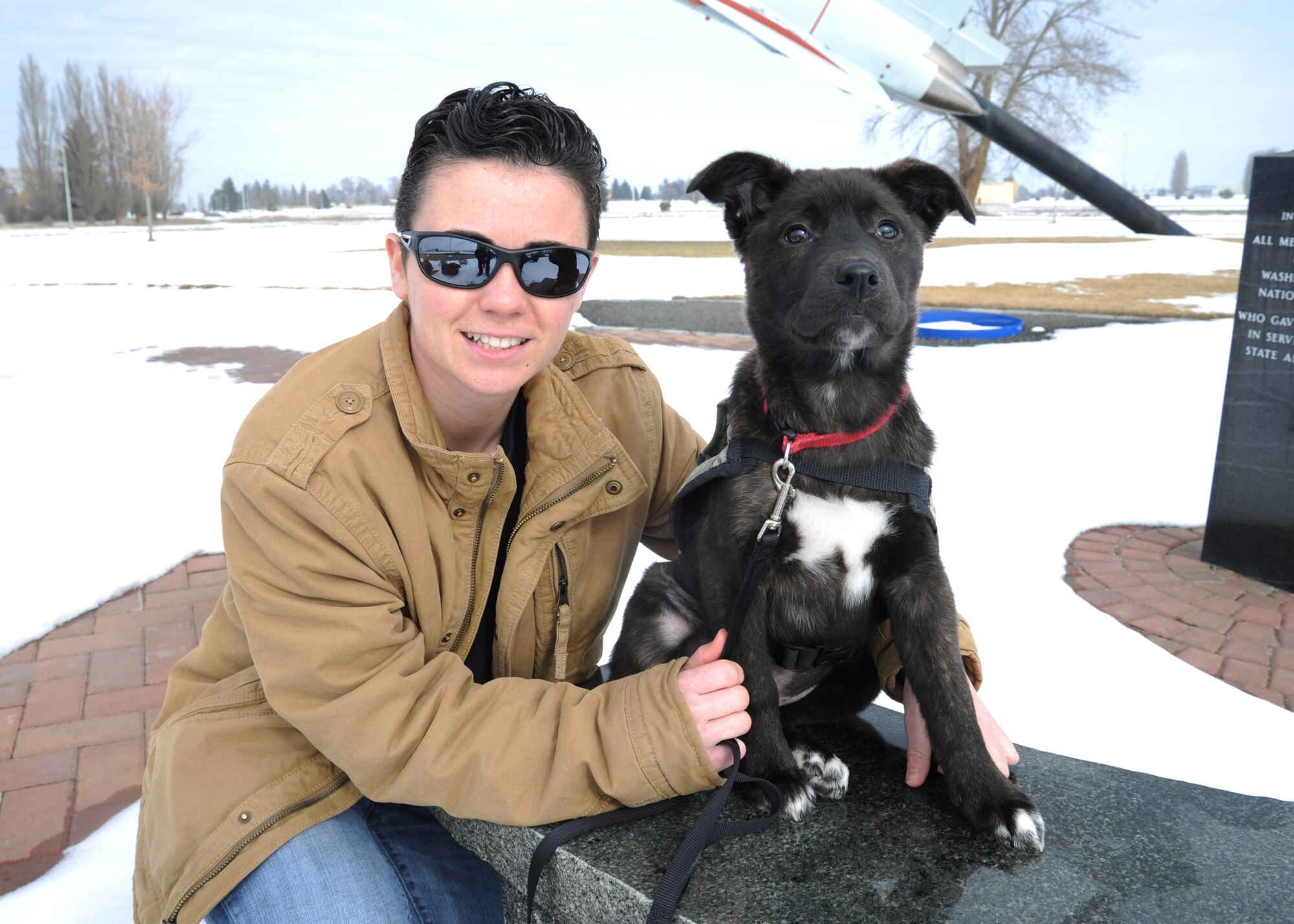 Staff Sgt. Melissa Schmalhorst, 92nd Security Forces Squadron military working dog handler, poses with Ashton, a blue-heeler mix, at Fairchild Air Force Base, Wash., Feb. 28, 2014. Schmalhorst volunteers with the Shepherds for Lost Sheep, Inc. and is fostering Ashton to become a service dog for a wounded veteran. (U.S. Air Force photo by Senior Airman Mary O'Dell/Released)