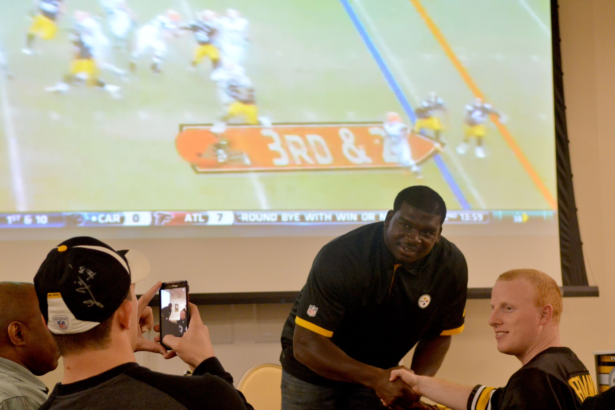 Lawrence Timmons, Pittsburgh Steelers #94 (center), shakes hand of a fan at Shaw Air Force Base, S.C., March 28, 2014, Timmons toured the base, meeting Airmen and getting to know the mission of the 20th Fighter Wing. He conducted an autograph signing and received the commander's coin from U.S. Air Force Col. Clay Hall, 20th Fighter Wing commander. (U.S. Air Force photo by Senior Airman Ashley Gardner/Released)