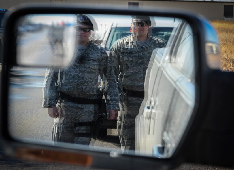 (from left to right) Senior Airman Kyle Schnetzler, 5th Security Forces Squadron desk sergeant and Airman 1st Class Sean Luna, 5th SFS installation entry controller, approach the vehicle of a simulated drunk driver at Minot Air Force Base, N.D., April 7, 2014. Instances of Airmen driving under the influence of alcohol or other substances has been steadily decreasing, with approximately 13 less incidents reported in the first quarter of 2014 than in 2011. (U.S. Air Force illustration/Senior Airman Stephanie Sauberan)