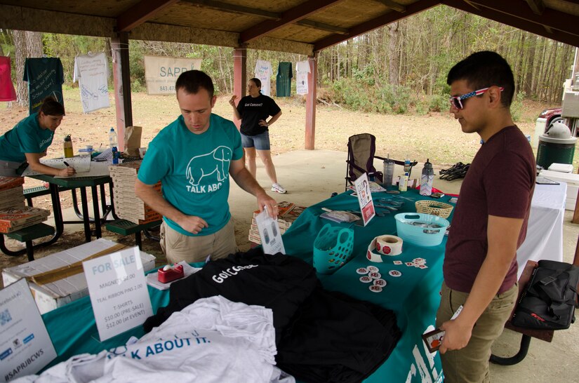 Petty Officer 1st Class Chris Bryant, a machinist’s mate assigned to Naval Nuclear Power Training Command, displays shirts, stickers and lapel pins during the Sexual Assault Prevention and Response kickball tournament, April 5, 2014, at Joint Base Charleston – Weapons Station, S.C. The kickball tournament was part of Sexual Assault Awareness Month and provided servicemembers the opportunity to support the Sexual Assault Prevention and Response program. (U.S. Navy photo/Petty Officer 3rd Class Jason Pastrick)