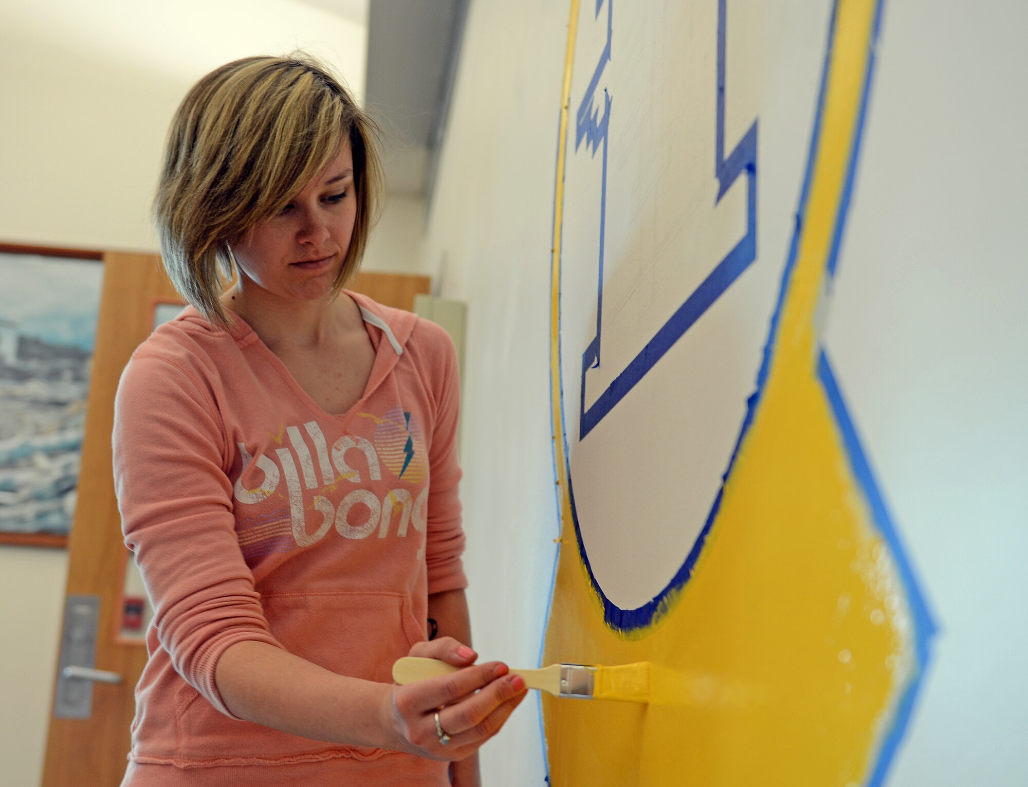 Senior Airman Danielle Snyder, 62nd Operations Support Squadron aircrew flight equipment journeyman, paints a mural of the 62nd OSS patch April 6, 2014 at Joint Base Lewis-McChord, Wash. Snyder volunteered to paint the mural to represent the squadron and raise morale. (U.S. Air Force photo/Airman First Class Jacob Jimenez)