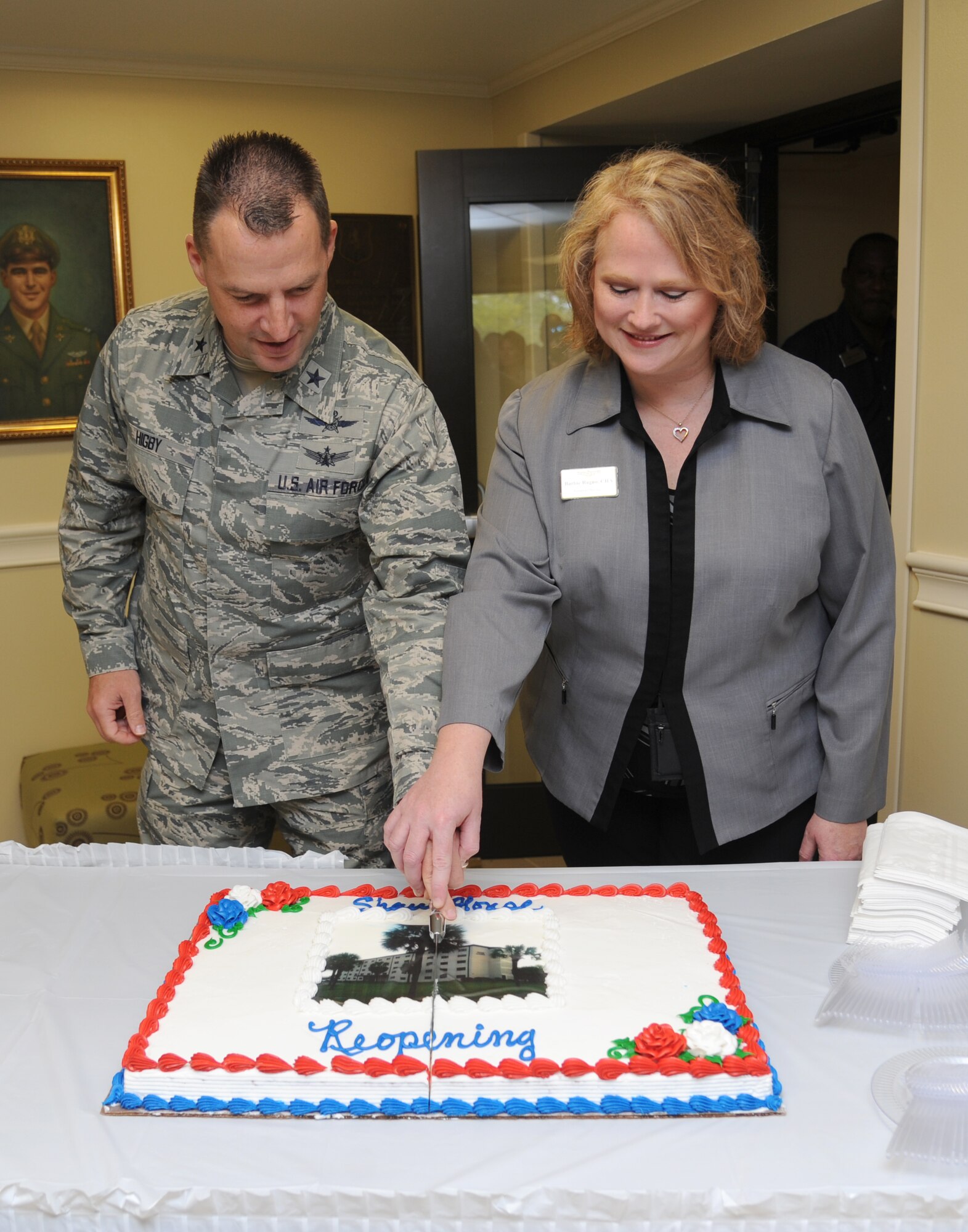 Brig. Gen. Patrick Higby, 81st Training Wing commander, and Barbie Ragno, 81st Force Support Squadron Inns of Keesler general manager, cuts a ceremonial cake during the Shaw House ribbon cutting ceremony April 3, 2014, at Keesler Air Force Base, Miss.  The Shaw House facility, named after Capt. William Stevenson Shaw, was originally constructed in 1966 and last renovated in 2013.  (U.S. Air Force photo by Kemberly Groue)