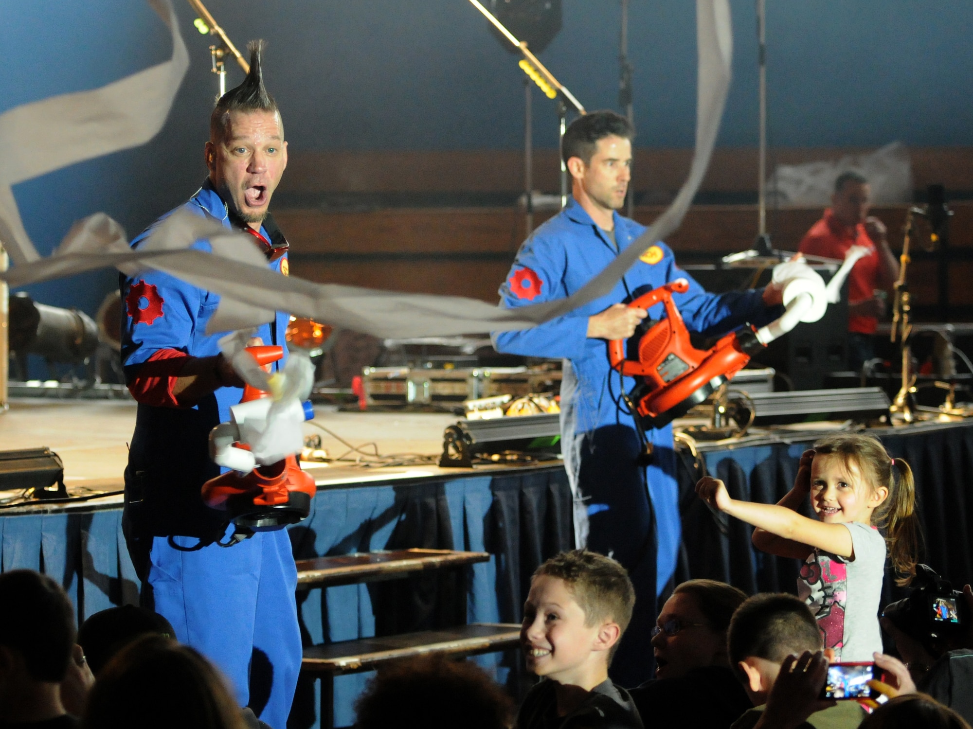 Scott Durbin, left, and Rich Collins shoot rolls of toilet paper over the crowd April 4, 2014, during a performance of their group the Imagination Movers at RAF Mildenhall, England. The Imagination Movers formed in 2003 in New Orleans and have since filmed three seasons of their award-winning television show. (U.S. Air Force photo by Tech. Sgt. Neal X. Joiner/Released)