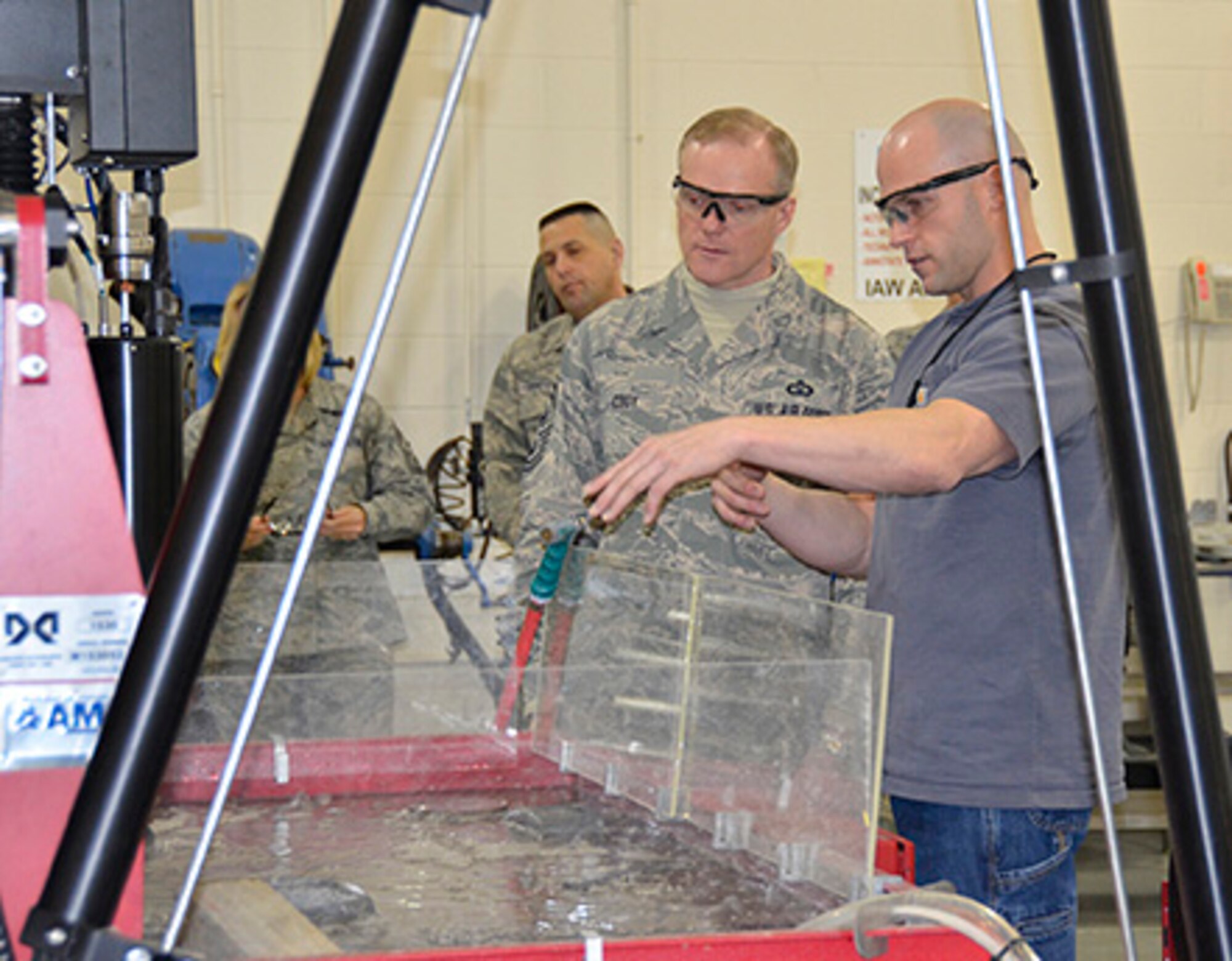 WRIGHT-PATTERSON AIR FORCE BASE, Ohio - Staff Sgt. Eric Whiteaker, 445th Maintenance Squadron Fabrication Flight metals technology journeyman, shows Chief Master Sgt. of the Air Force James A. Cody  how the MAXIEM abrasive water jet machine makes cuts in metal during his visit to the wing March 21. The machine cuts materials, such as marble, granite, glass, tile, stone, composites, as well as metals such as aluminum, tool steel, titanium, and carbon fiber. It is used to make/manufacture support parts for the C-17 Globemaster III and ground support equipment. (U.S. Air Force photo/Stacy Vaughn)