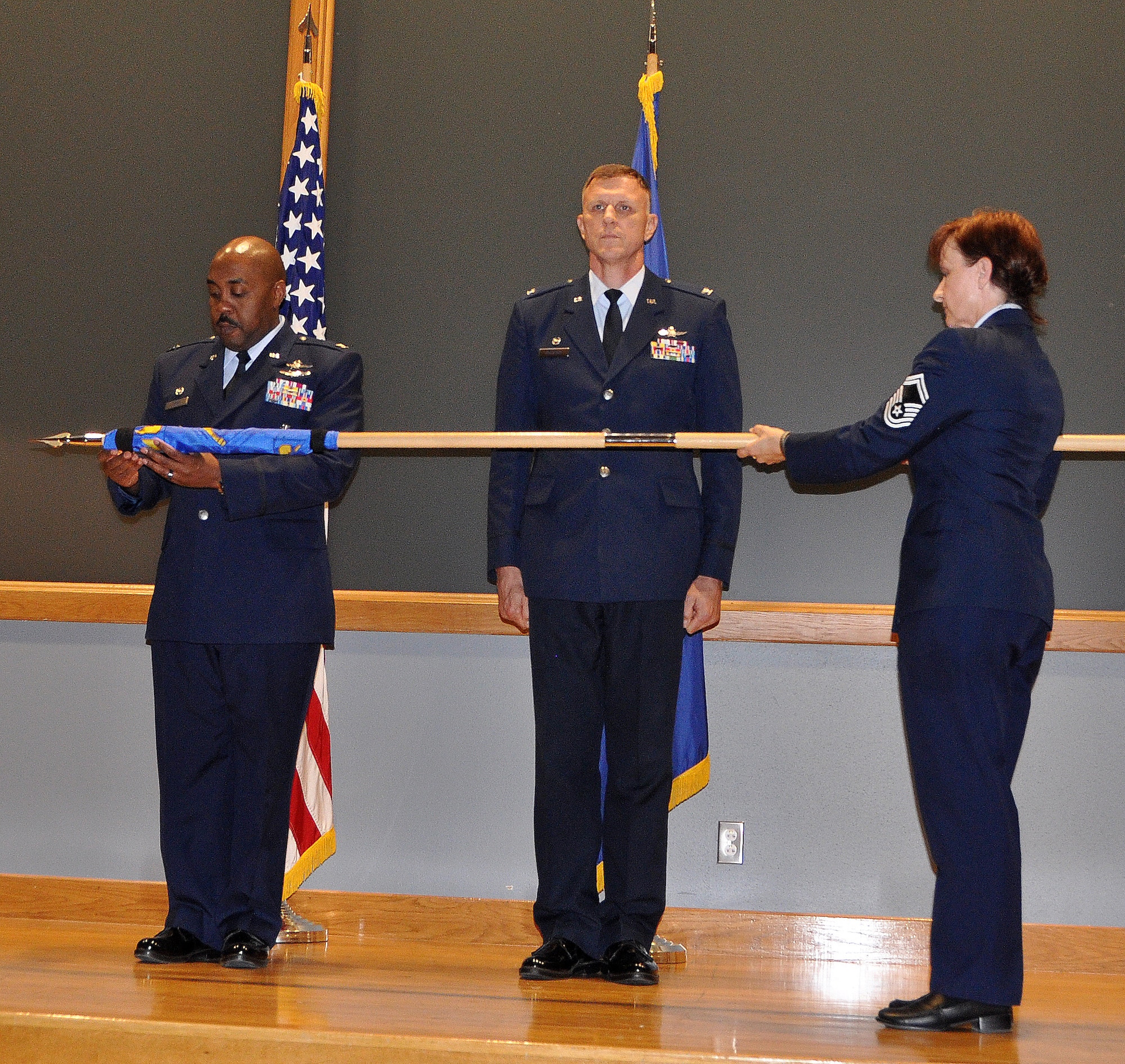 Col. Lloyd Terry Jr., 960th Cyberspace Operations Group commander prepares to unfurl the 854th Combat Operations Squadron’s guidon held by Senior Master Sgt. Kim MacFarlane, 854th COS superintendent at the squadrons activation ceremony April 5 at the Kelly Fitness Center auditorium, Joint Base San Antonio-Lackland, Texas.  Col. Mark Melcher (center), 854th COS commander, assumed command of the former detachment a year ago to build the unit to squadron strength and is continuing his focus on hiring qualified people to support the Air Force cyberspace command and control mission. (U.S. Air Force photo/1st Lt. Lori Fiorello)