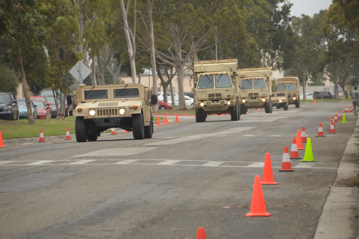 Military vehicles carrying Soldiers from the 340th Bravo Company drive through the main gate at the 146th Airlift Wing to meet with  U.S. Air National Gaurd members in Port Hueneme, Caif., during a Joint Reception Staging Onward Integration exercise training on March 1, 2014. (Air National Guard photo by Airman First Class Madeleine Richards)