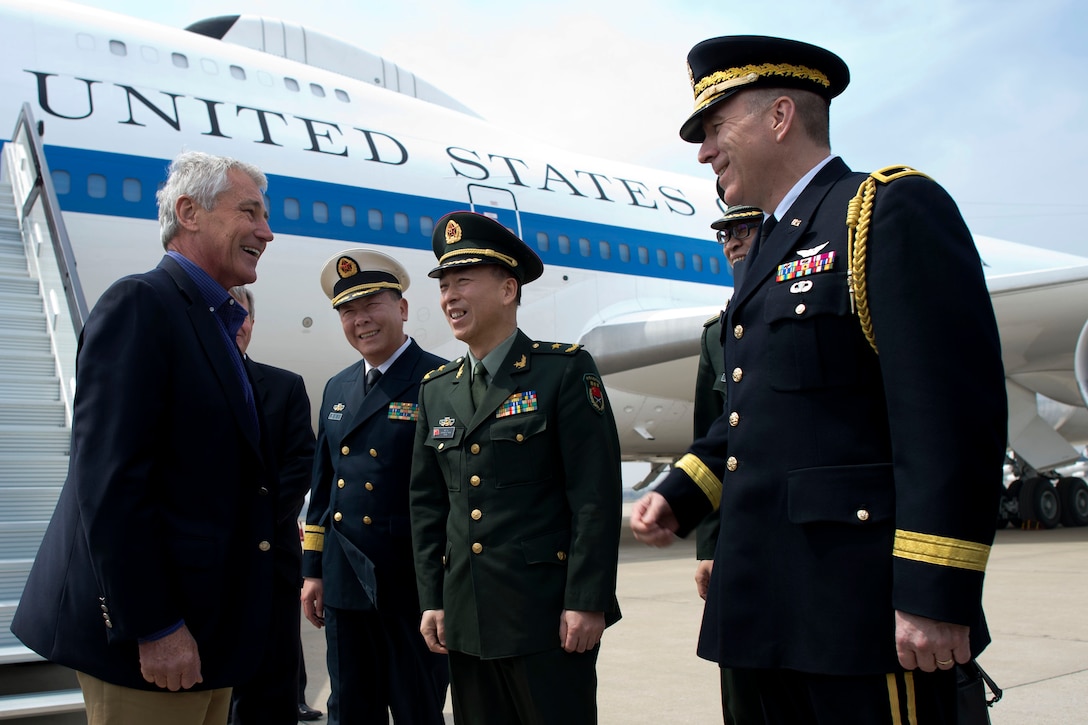 U.S. Defense Secretary Chuck Hagel, left, is greeted by U.S. Army Brig. Gen. Mark W. Gillette, right, U.S. defense attaché to China, and Chinese military officers in Qingdao, China, April 7, 2014. While in the city, Hagel became the first foreigner to visit the Chinese aircraft carrier Liaoning.
