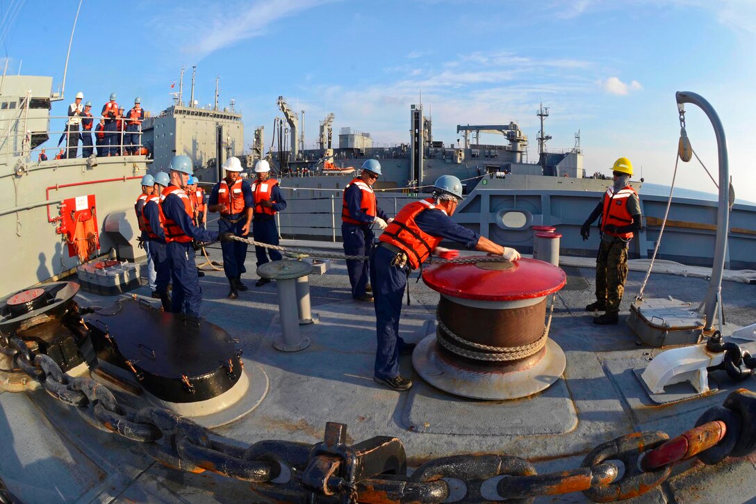 U.S. sailors and Military Sealift Command civilian mariners aboard the submarine tender USS Frank Cable haul in line during a replenishment with the Military Sealift Command ship USNS Cesar Chavez in the Pacific Ocean, April 3, 214