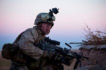 Lance Cpl. Nathan Chandler, a Logan, Ohio, native and machine gunner with 1st Battalion, 9th Marines, hunkers down behind a compound wall during a firefight with insurgents near the Bari Gul Bazaar, Nad Ali District, Helmand province, Afghanistan, Dec. 4. Nearly 100 Marines and coalition allies engaged in a prolonged firefight with insurgents while patrolling the area to interdict Taliban movements and weapons caches and gather intelligence around the bazaar. The interdiction force landed by helicopter during the cover of night and began sweeping through the area with the help of Afghan forces and interpreters before engaging Taliban fighters in a firefight that lasted nearly four hours. (Photo By: Cpl. Paul Peterson)