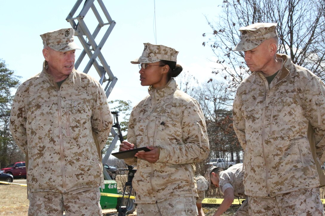 From the left, Lt. Gen. Kenneth Glueck Jr., commanding general of Marine Corps Combat Development Command, Sgt. Jessica Wright, a field wireman currently serving as an augment to Security Battalion, MCB Quantico, and Brig. Gen. Frank Kelley, commanding general for Marine Corps Systems Command, discuss the Autonomous Aerial Cargo/Utility System prototype during a demonstration at Marine Corps Base Quantico on March 20, 2014. The system of software and sensors provides autonomous approach and landing capabilities to rotary aircraft, manned or unmanned.