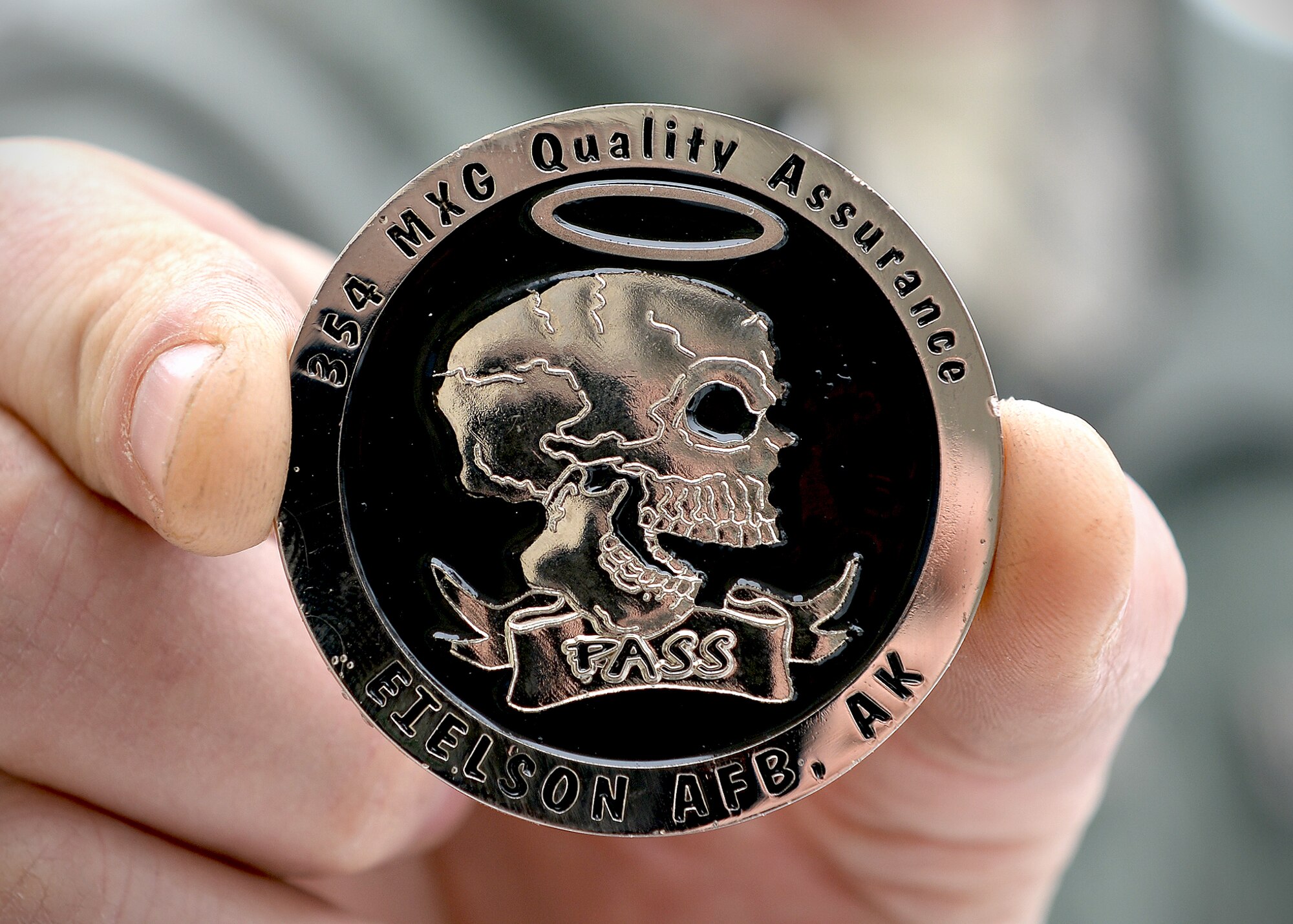 The pass-fail challenge coin from the 354th Maintenance Group quality assurance flight symbolizes the specialty and importance of the inspections they perform. Quality assurance Airmen are maintenance experts who work to identify trends, provide support and advice, and handle difficult or unique maintenance situations from the sections they inspect daily. (U.S. Air Force photo by Staff Sgt. Shawn Nickel/Released)